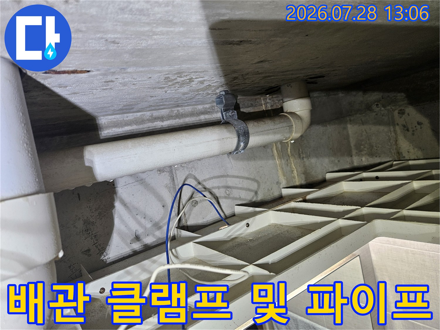 벽체에 고정된 하얀색 배수관과 금속 클램프의 상세 모습