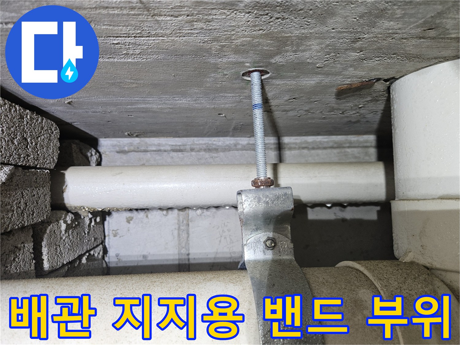 하얀색 배관을 단단하게 잡아주는 금속제 고정 밴드와 볼트 사진