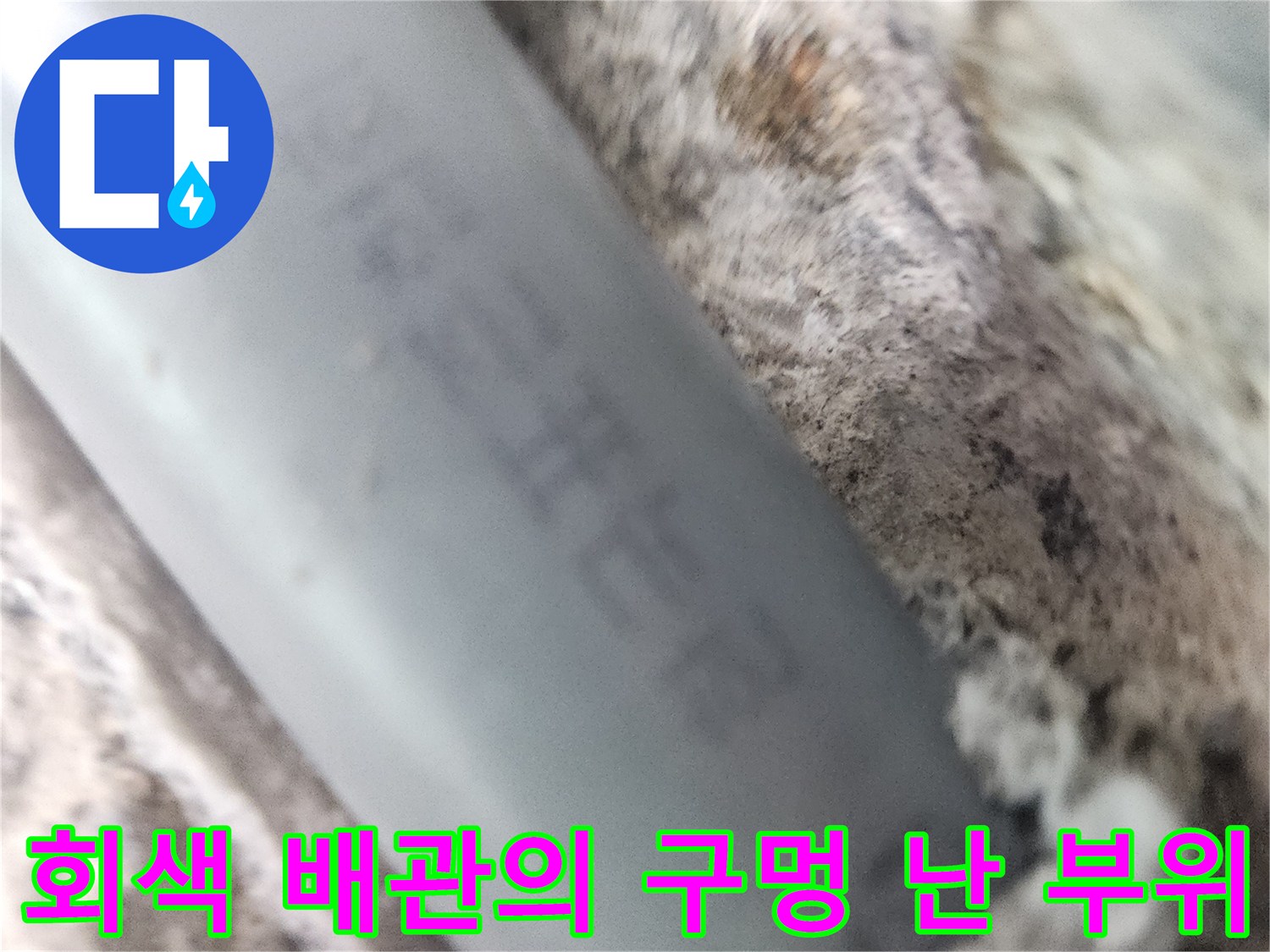 벽면 내부에서 발견된 회색 배관의 파손된 상태 사진입니다.