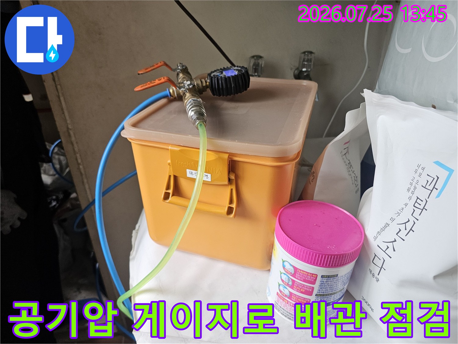 오렌지색 박스 위에 설치된 압력계와 투명한 호스로 배관을 체크하는 모습