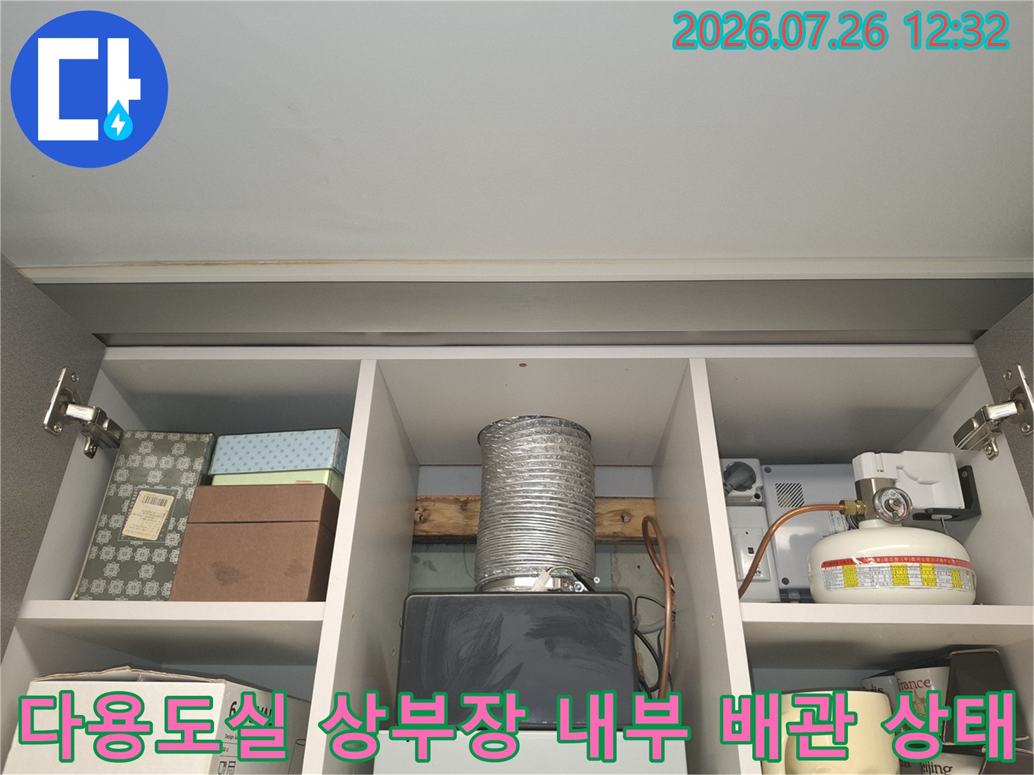 다용도실 수납장 내부의 은색 자바라 배관과 가스 보일러 장비가 설치된 모습