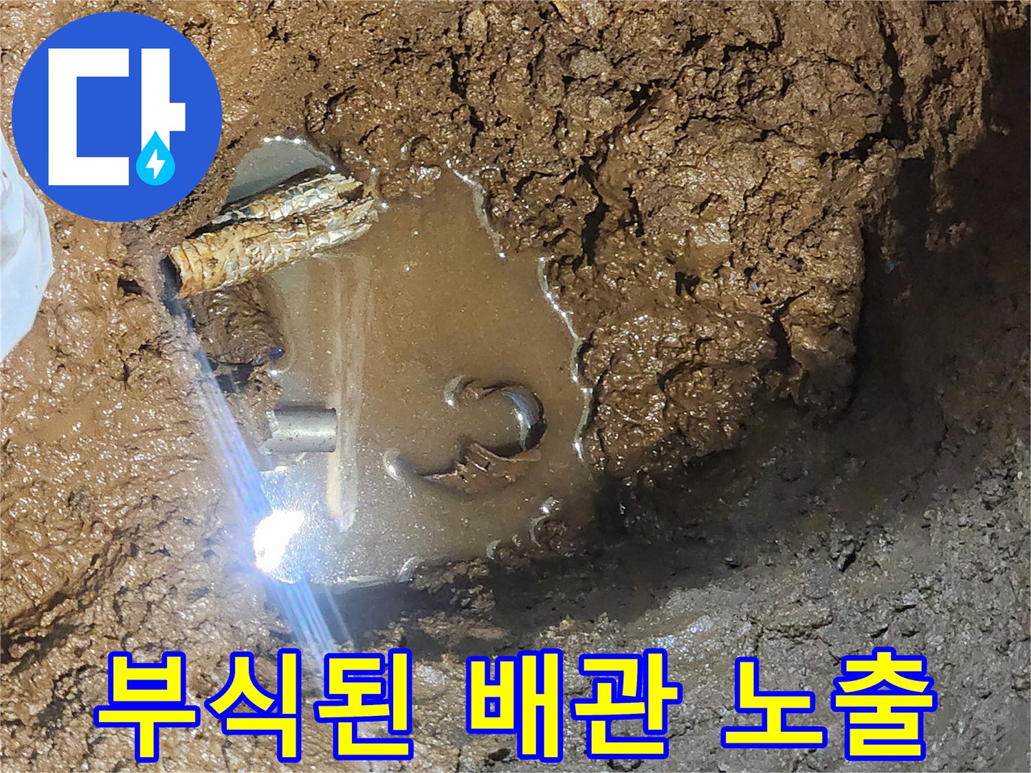 흙 속에 드러난 부식된 배관 - 누수가 진행 중인 현장 상황입니다.