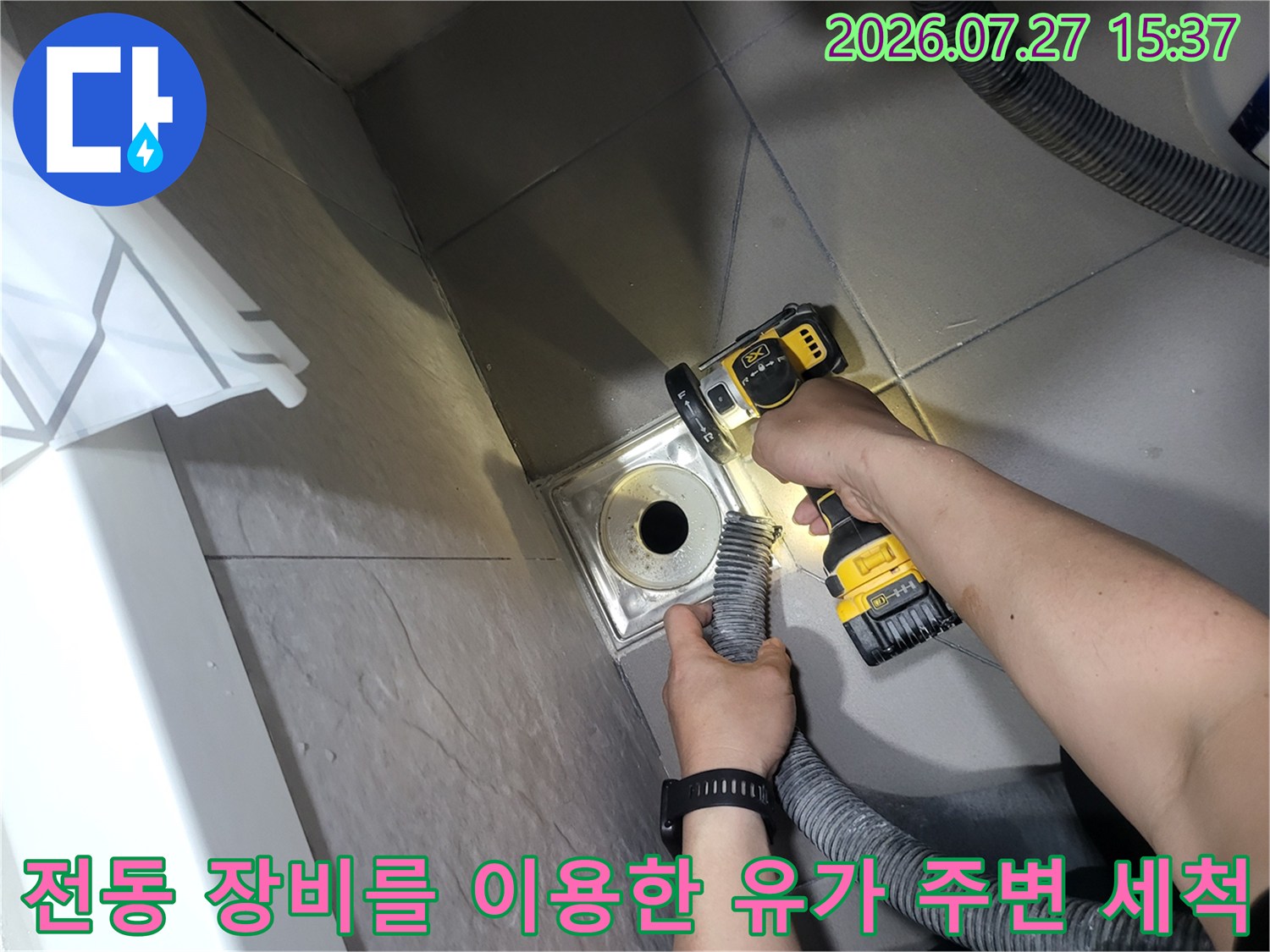 노란색 전동 청소 도구를 활용해-배수구 입구와 타일 틈새의 오염물을 제거하는 장면