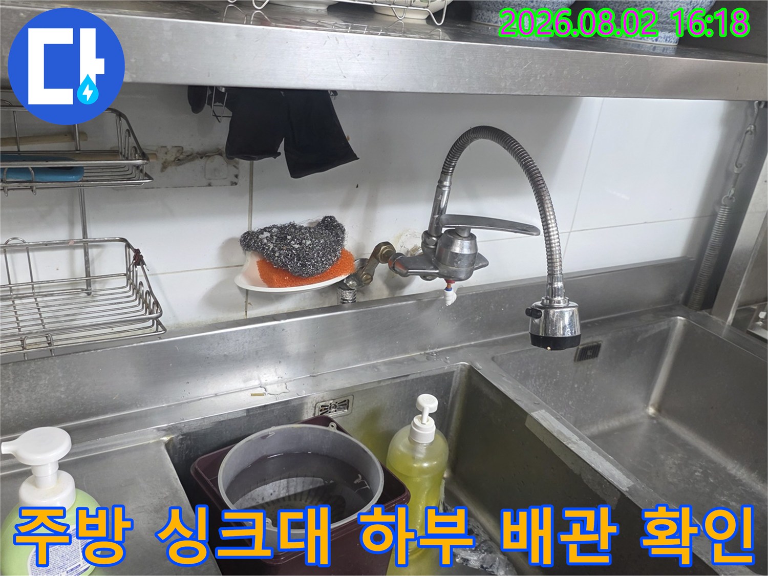 싱크대 밑 공간에서 수전과 연결된 수도용 배관을 정밀하게 점검하는 모습