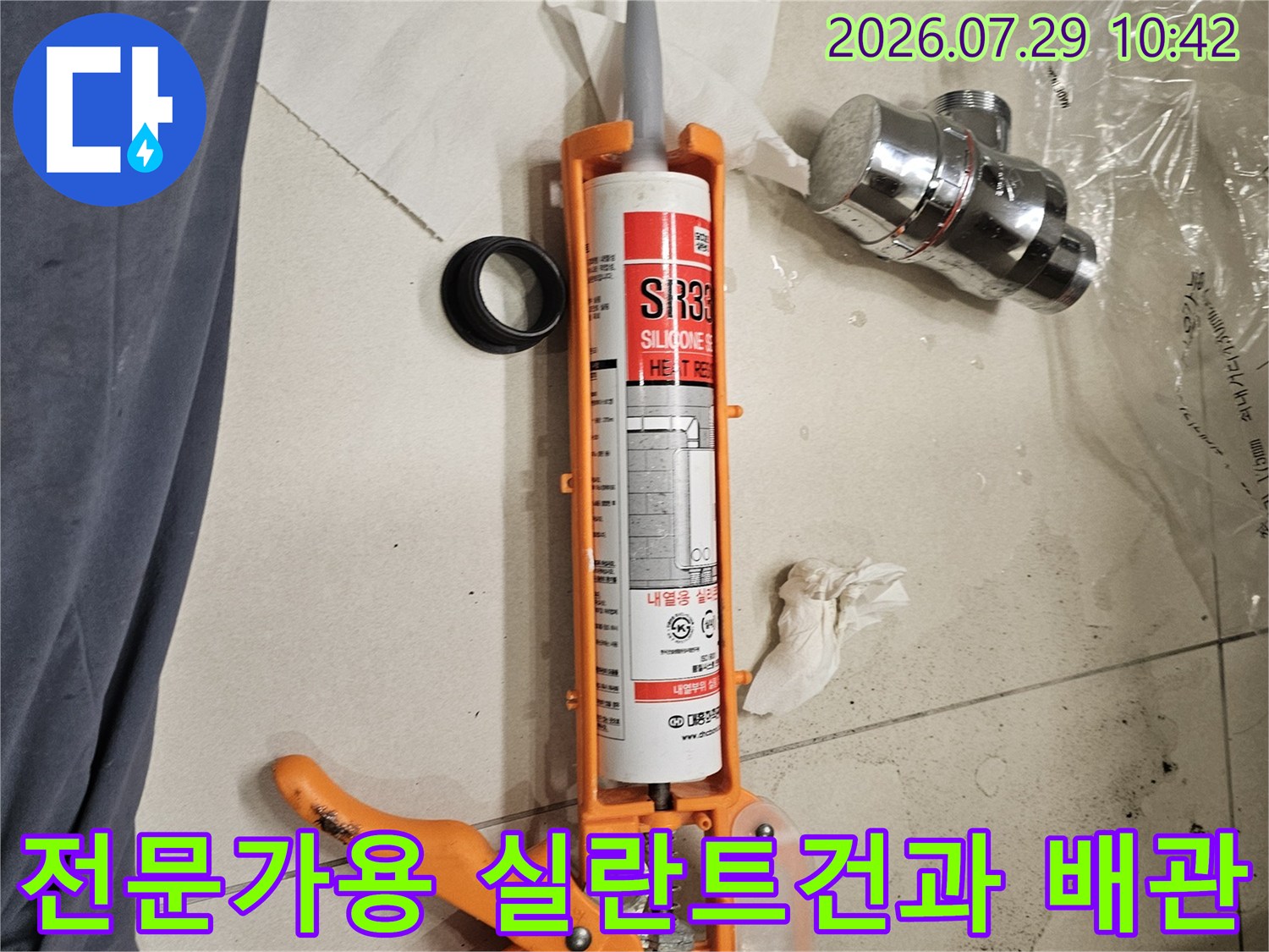 오렌지색 실란트 건에 장착된 실리콘 카트리지와 세면대 배관 부속