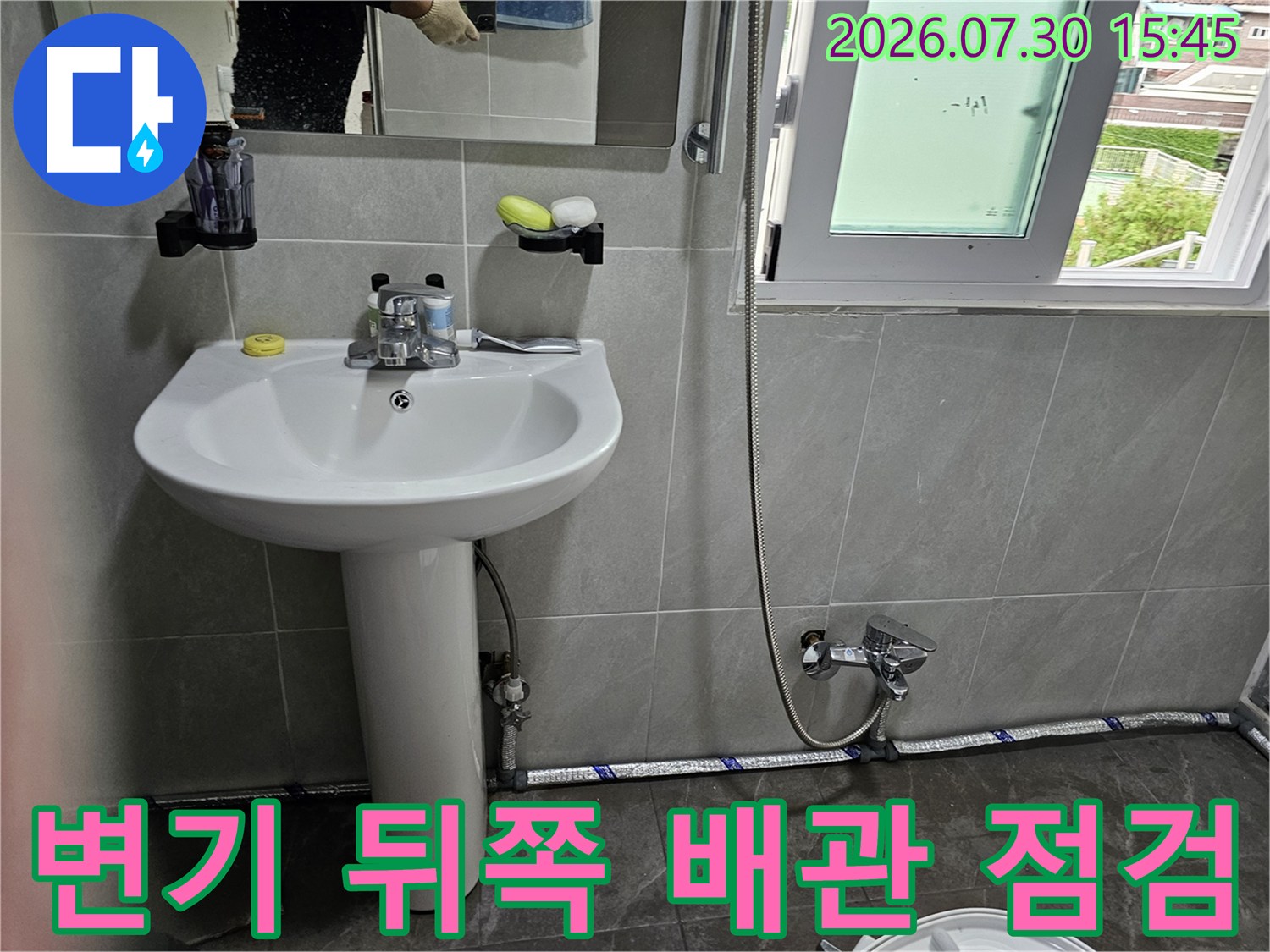 화장실 변기 옆 수직으로 세워진 하얀색 파이프와 연결 부품들