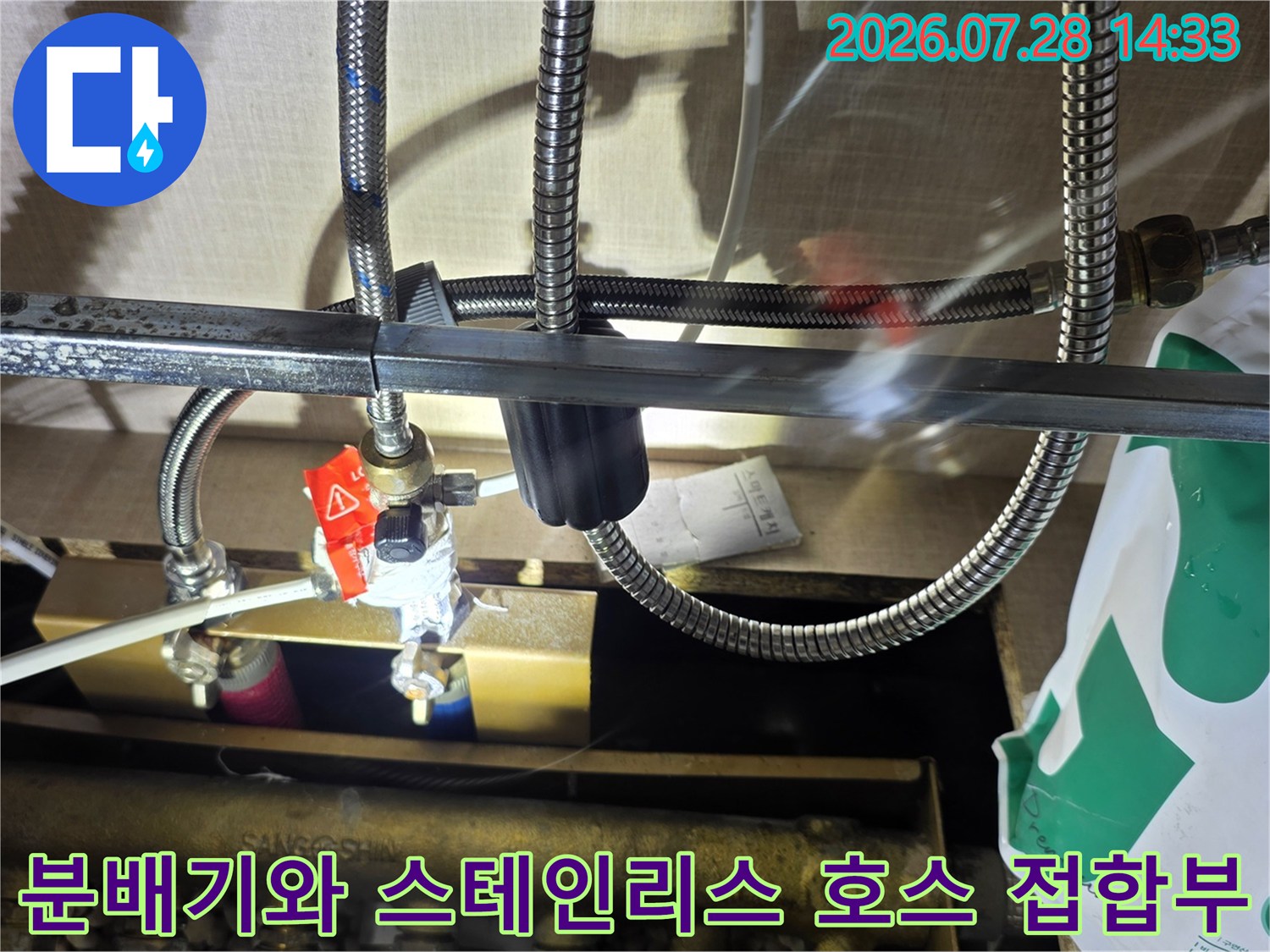 빨간색 조절 밸브가 달린 분배기에 은색 주름관이 체결되어 있는 모습-누수 발생 부위