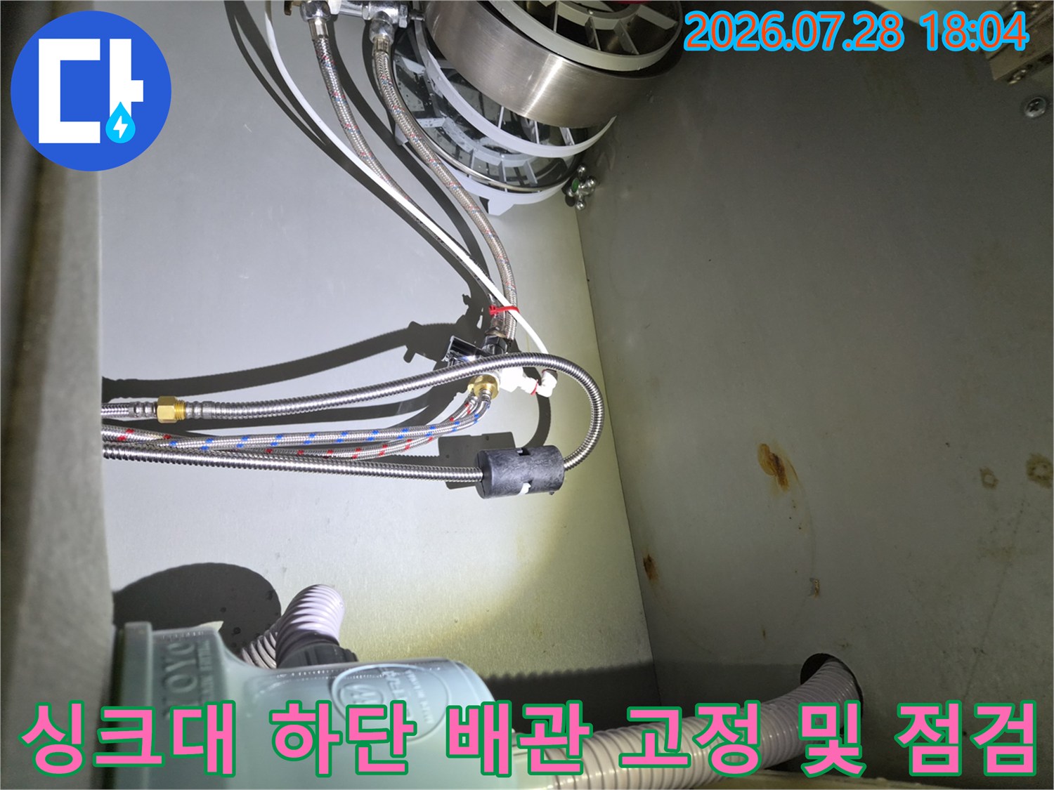 식기세척기 연결 부위의 복잡한 호스들을 정밀하게 점검하는 모습