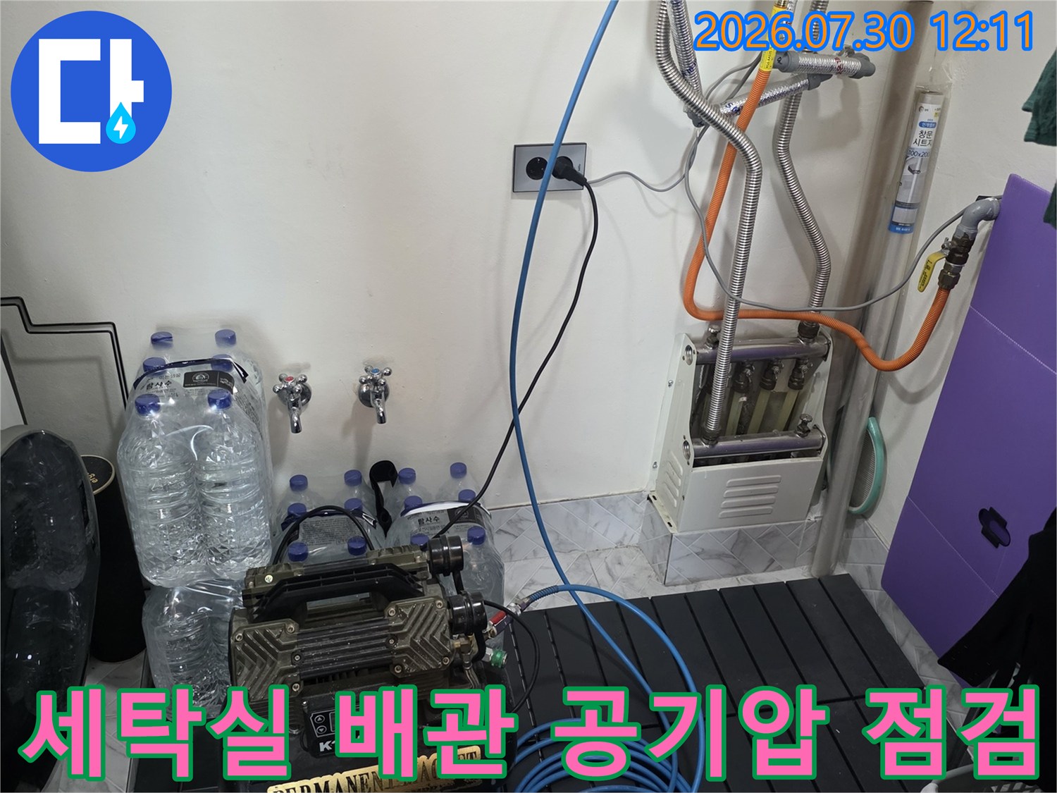 세탁실 내 노출된 배관에 공기압 게이지를 연결하여 누수 여부를 정밀하게 점검하는 모습