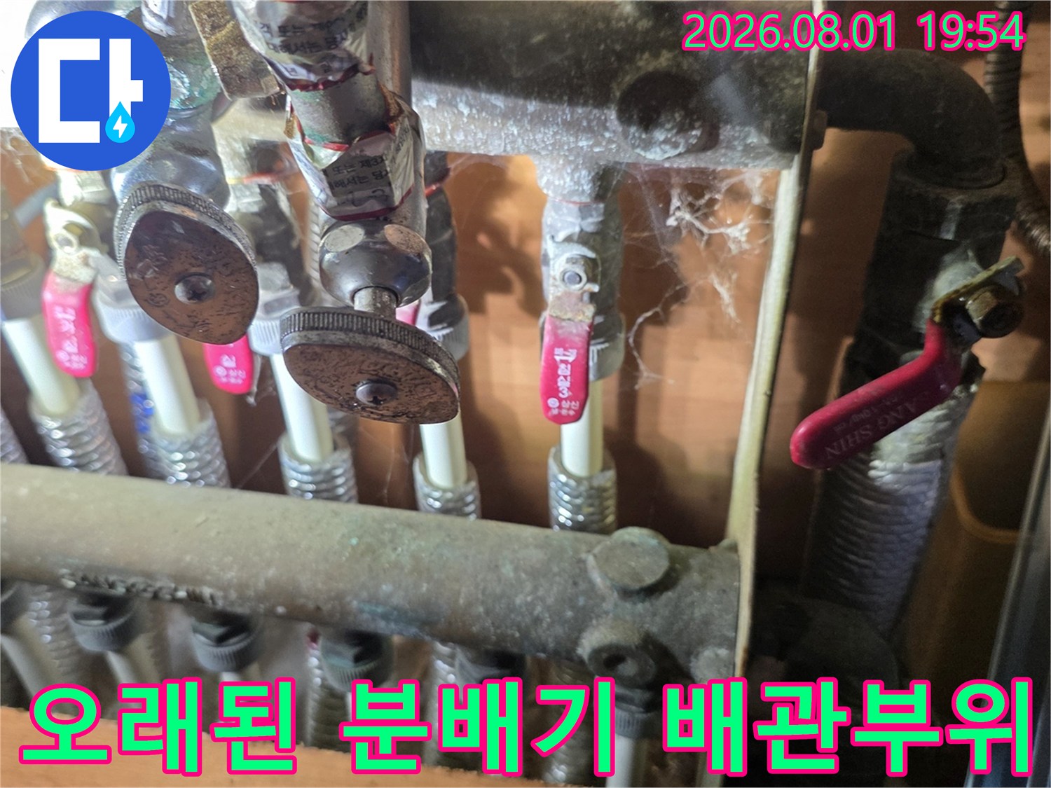 먼지가 덮인 노후한 배관과 금속성 분배기의 상세 모습
