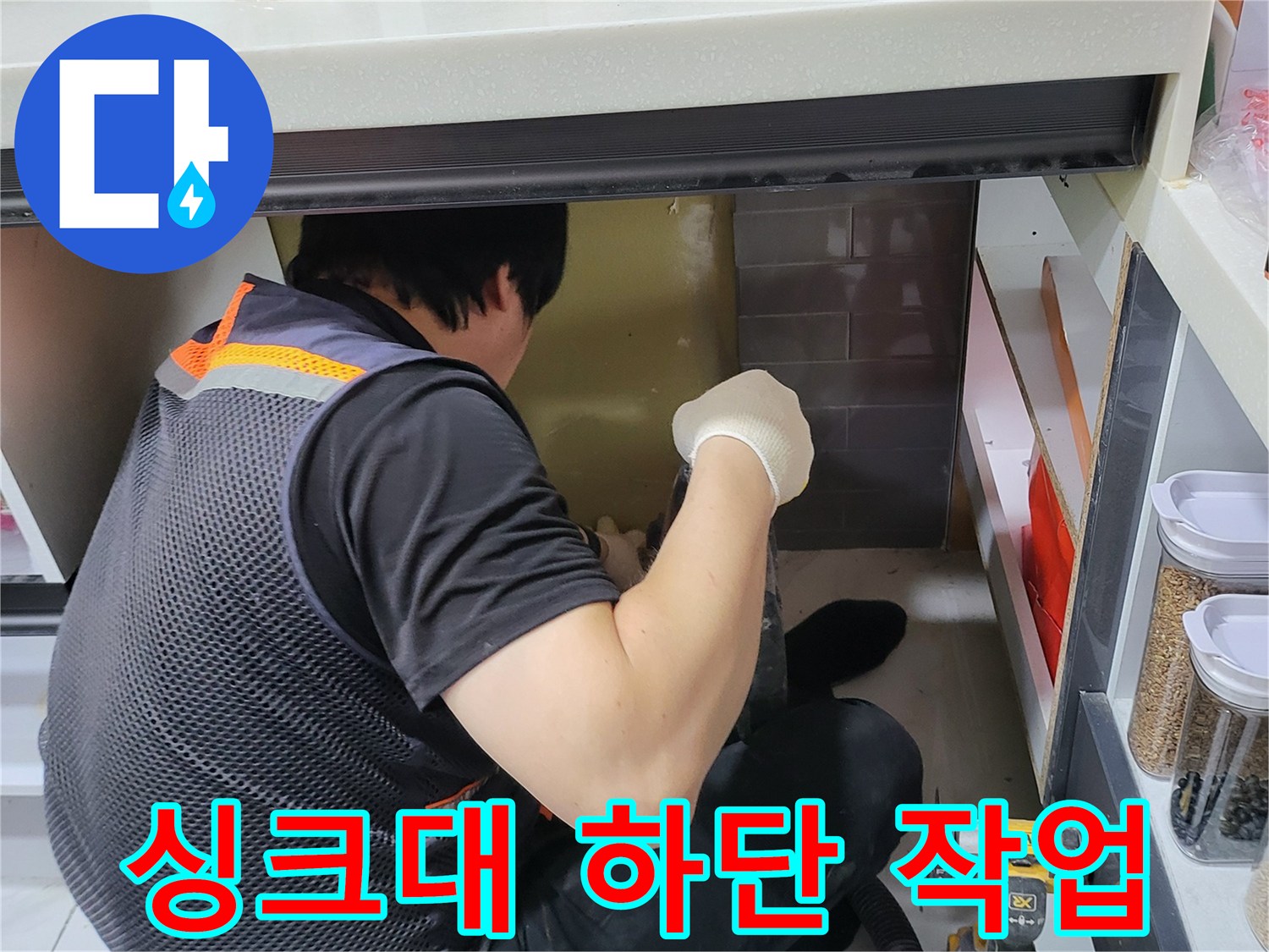 싱크대 아래 공간에서 누수 지점을 찾기 위해 작업 중인 모습