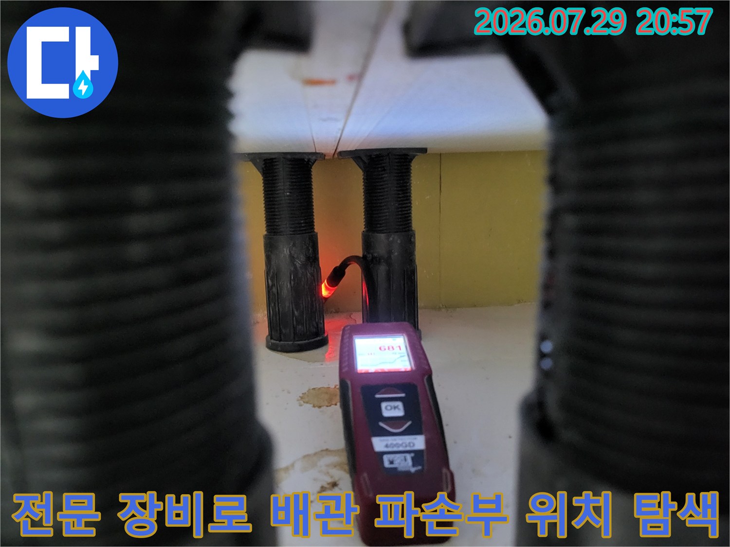 싱크대 하단 굴착 공간 내에서 가스 탐지기를 사용하여 온수 배관의 누수 지점을 정밀하게 확인하는 장면입니다.