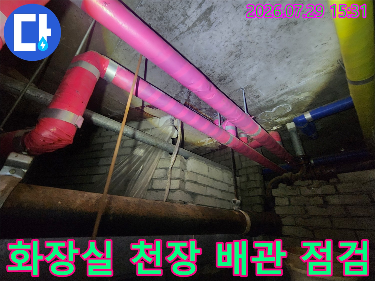 분홍색과 파란색 보온재로 감싸진 화장실 천장 배관을 정밀 점검하는 모습