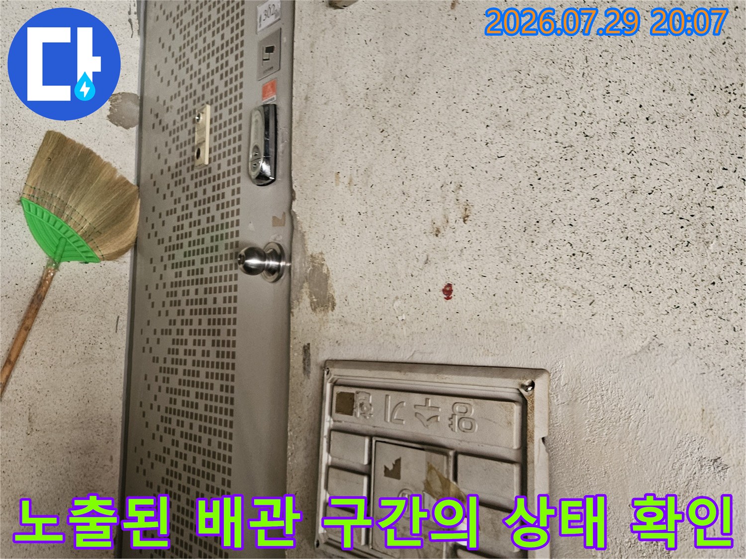 벽면 마감재 손상 부위와 노출된 금속판 근처 배관 점검