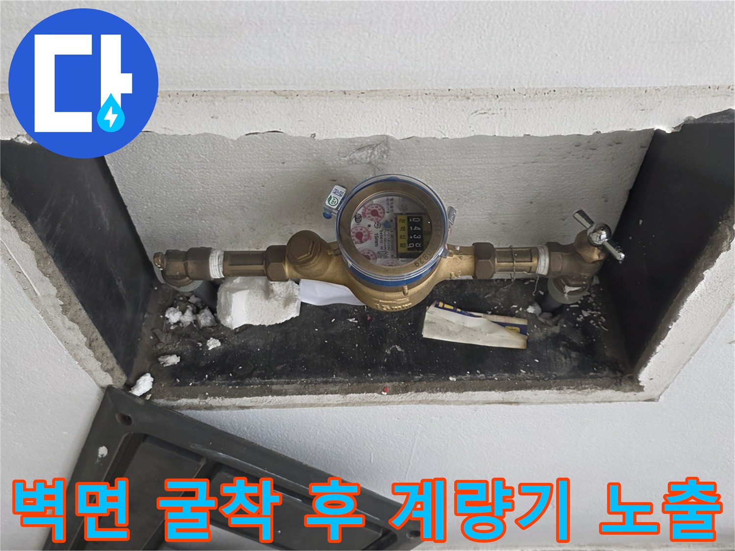 콘크리트 벽을 파내어 드러낸 수도 계량기와 밸브 부품