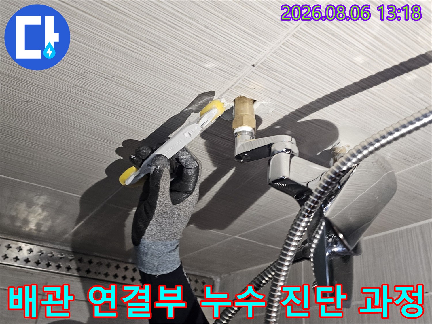 샤워기 배관과 수전의 연결 부위를 장비로 점검하여 문제 지점을 찾는 모습