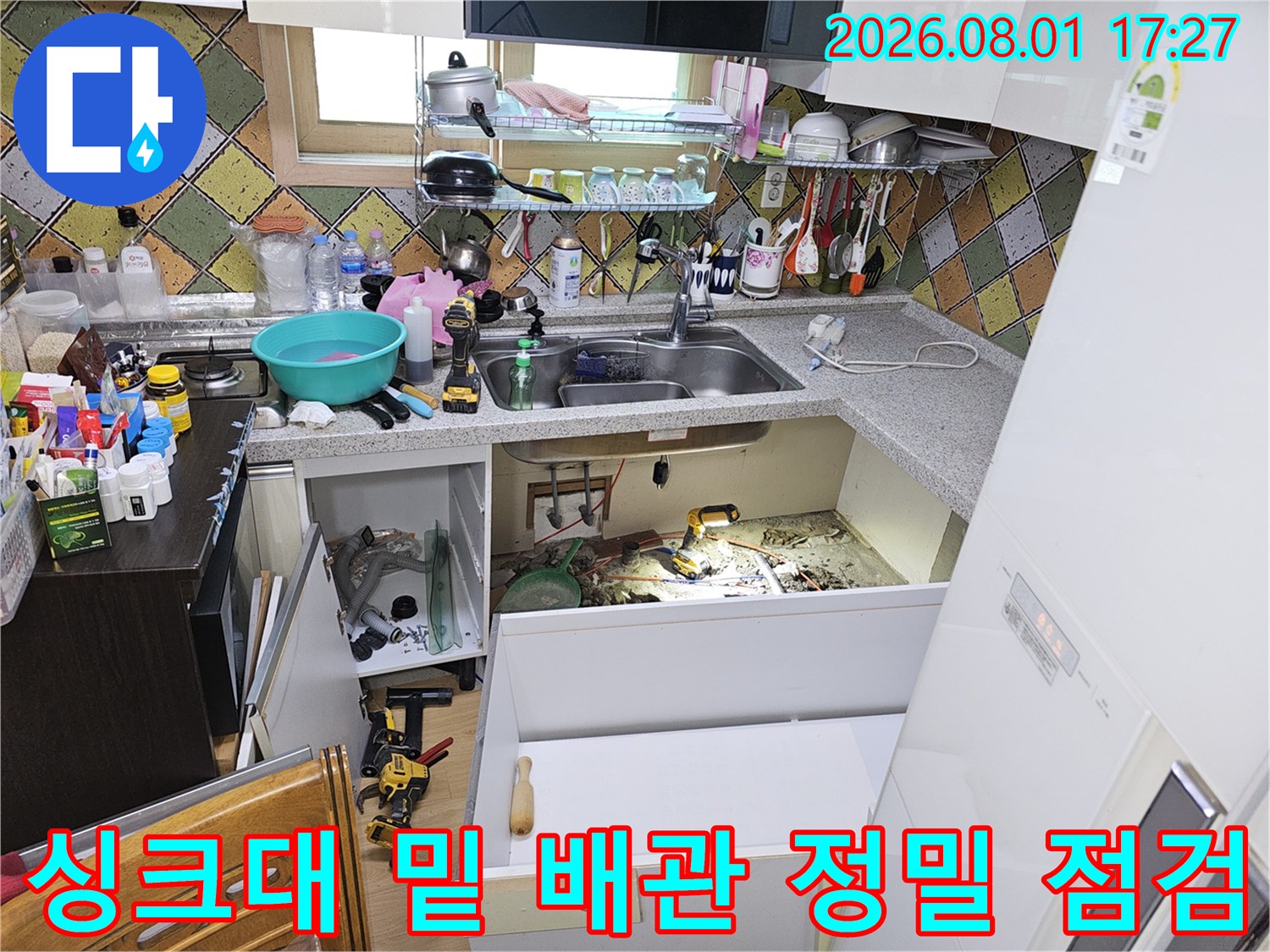 누수 지점을 찾기 위해 싱크대 하부 공간에서 배관을 조사하는 모습