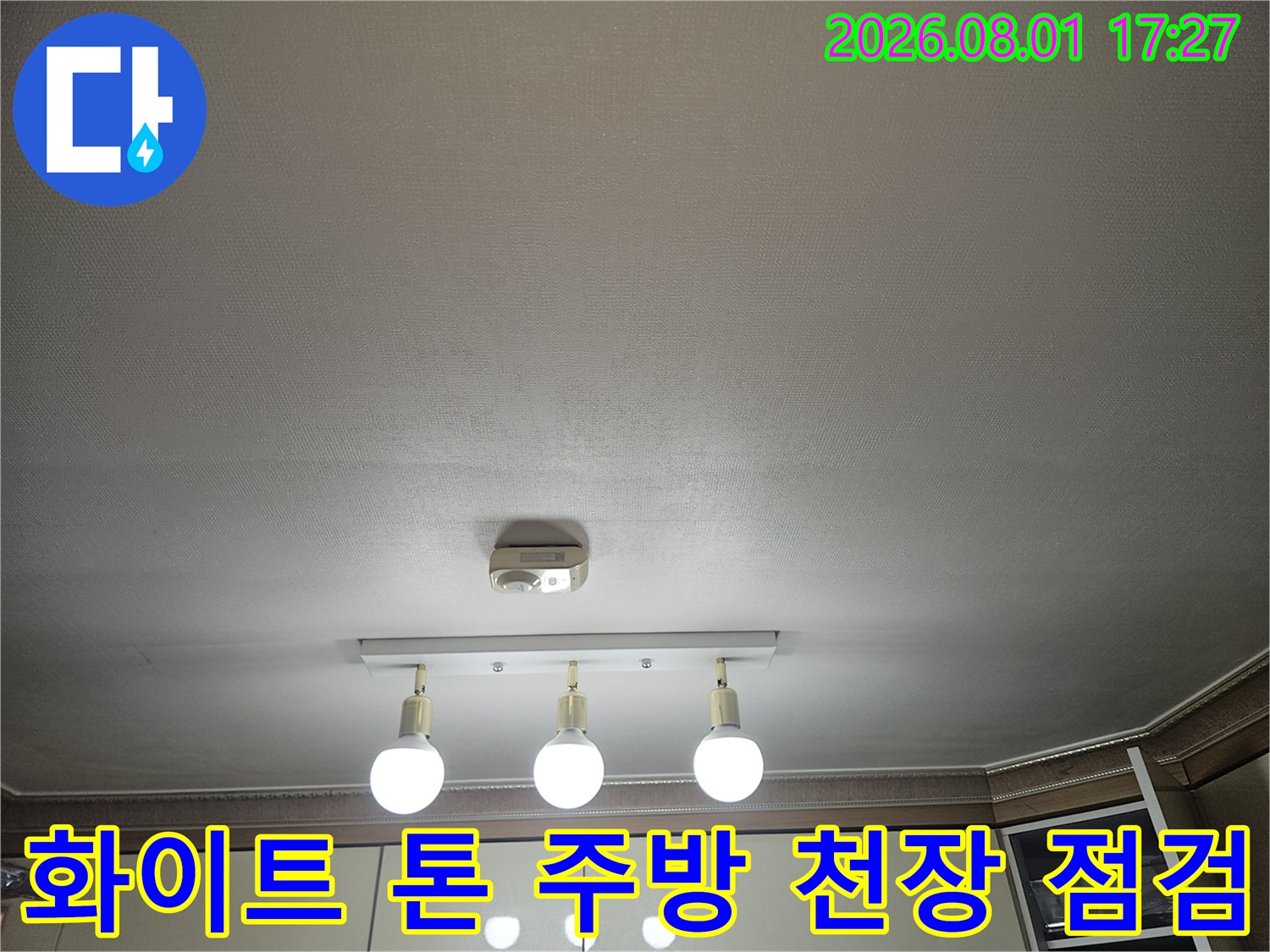 밝은 색상의 마감재와 전등이 설치된 거실과 연결된 주방 공간