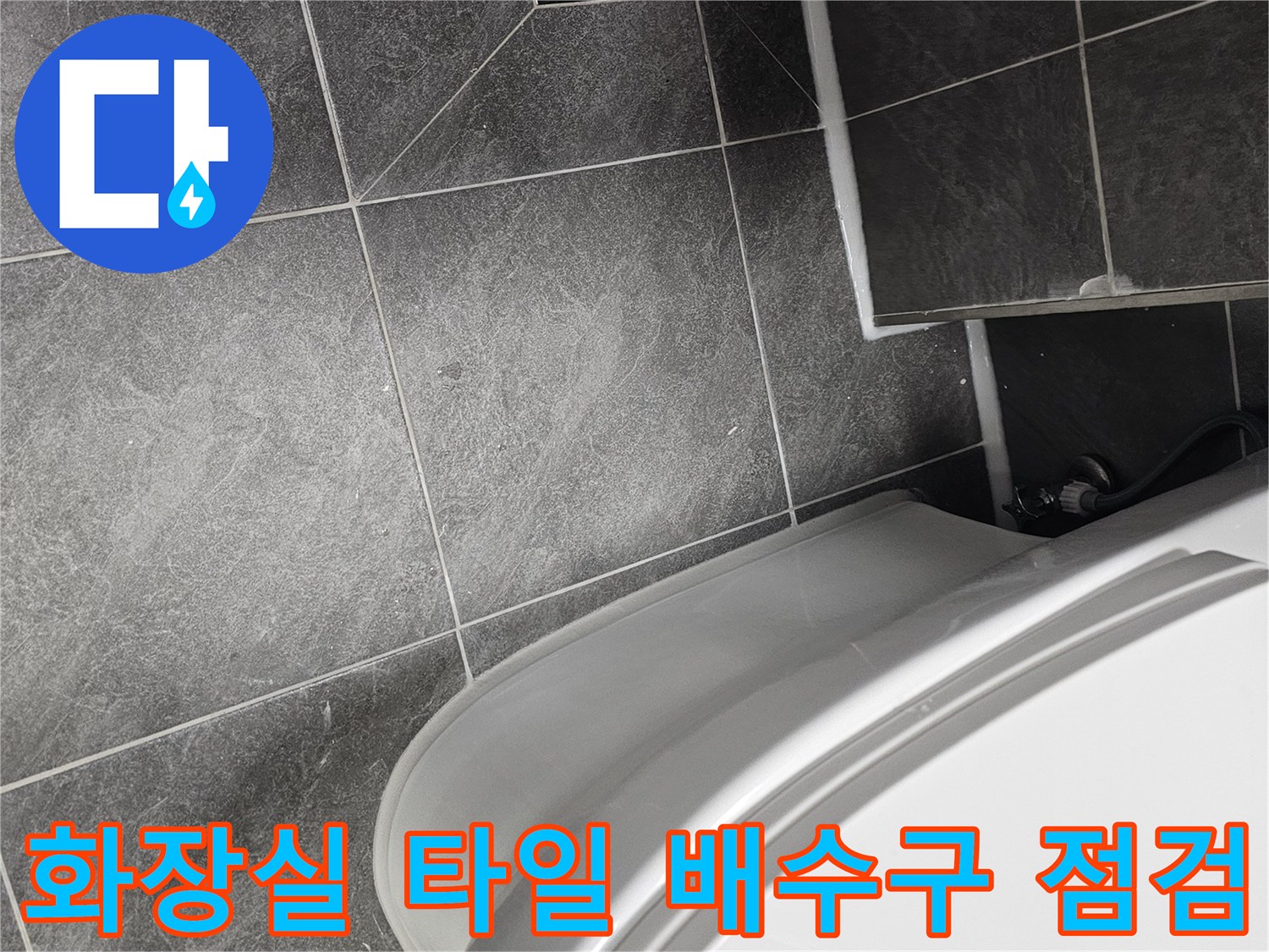 양변기와 검은색 배수구 덮개가 있는 욕실 바닥면의 모습
