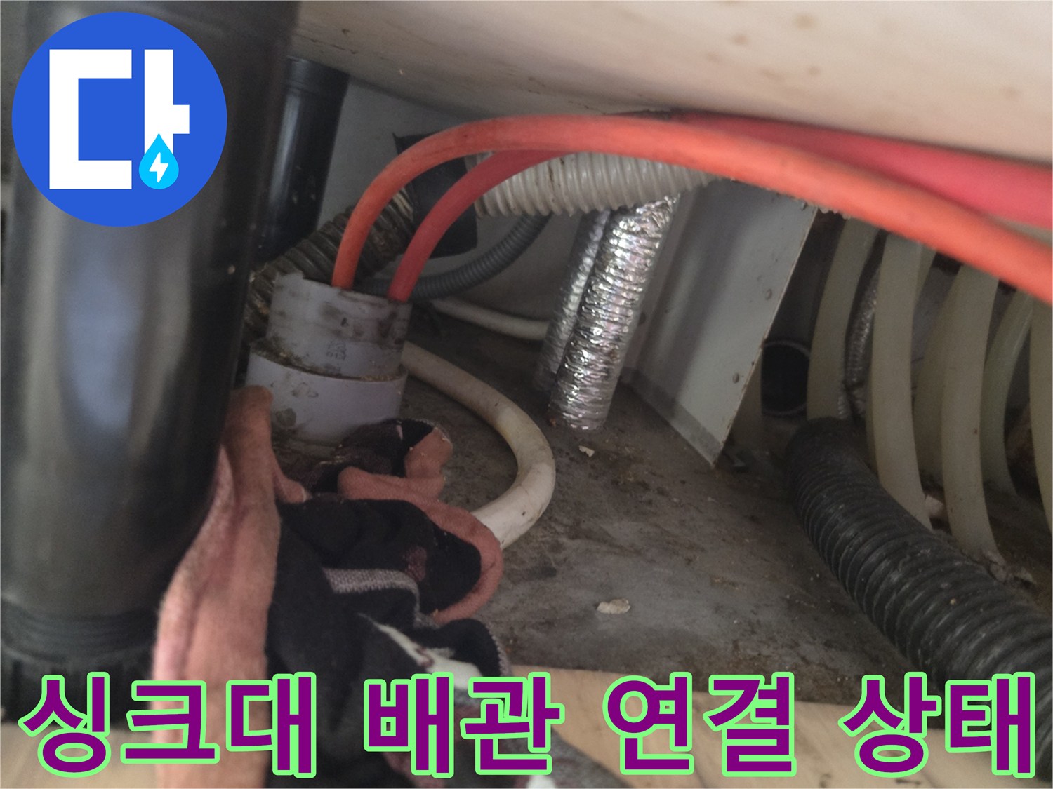 싱크대 하단 배수 호스와 은색 자재가 노출된 현장 사진