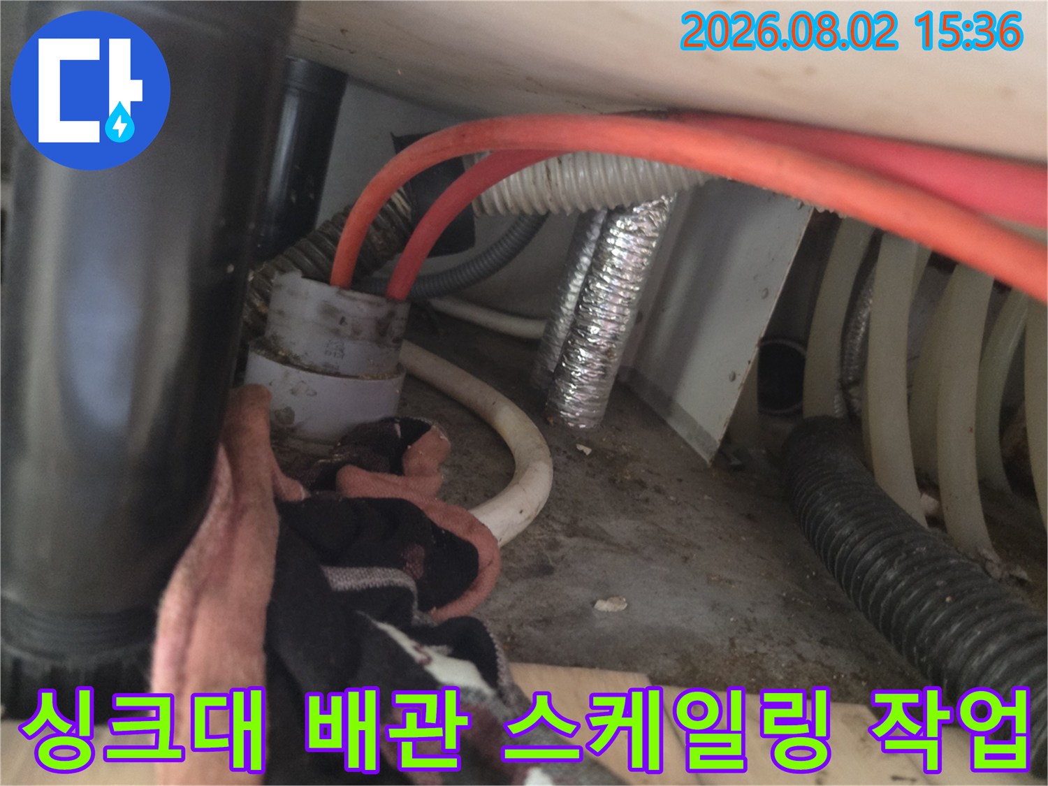 싱크대 하부 배관 내부에 이물질을 제거하는 샤프트 장비와 절연체 배관이 노출된 현장 사진