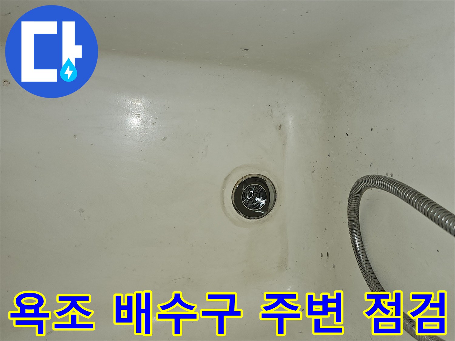 화장실 욕조 하단에 위치한 배수구와 샤워 호스 상세 모습