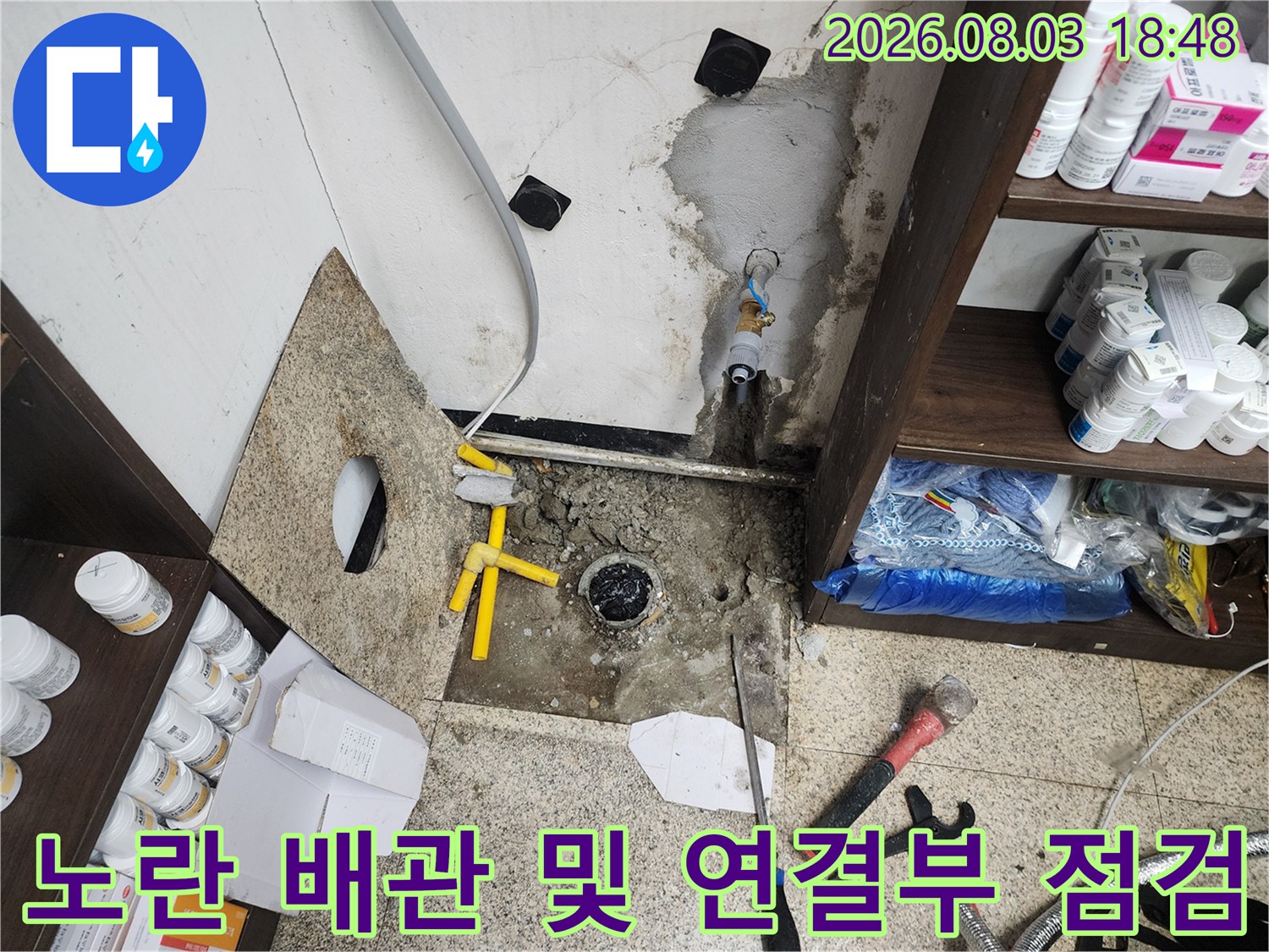 노출된 노란색 배관과 연결 호스를 포함한 싱크대 하부 배관 구조