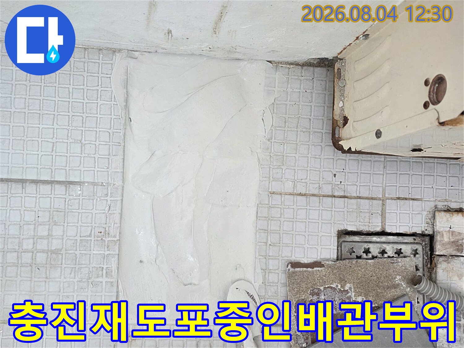 공사 마무리 단계에서 흰색 퍼티를 사용하여 배관 주변을 정리하는 장면