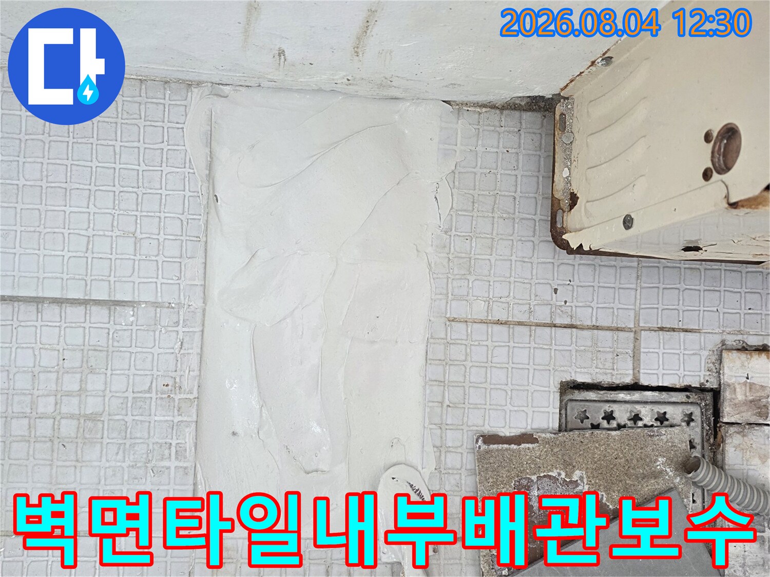 수리가 완료된 배관 부위에 흰색 충진재로 꼼꼼하게 마감 처리를 하는 모습