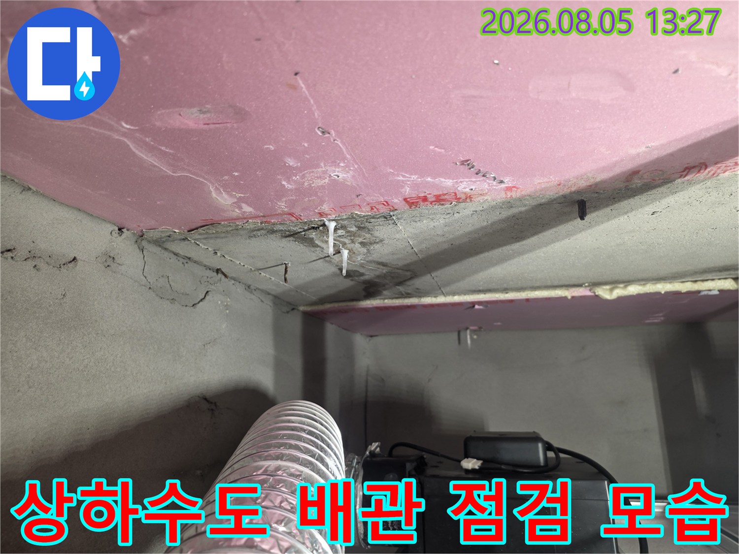 분홍색 천장재 아래 노출된 배관과 누수 측정 장비 연결 상태