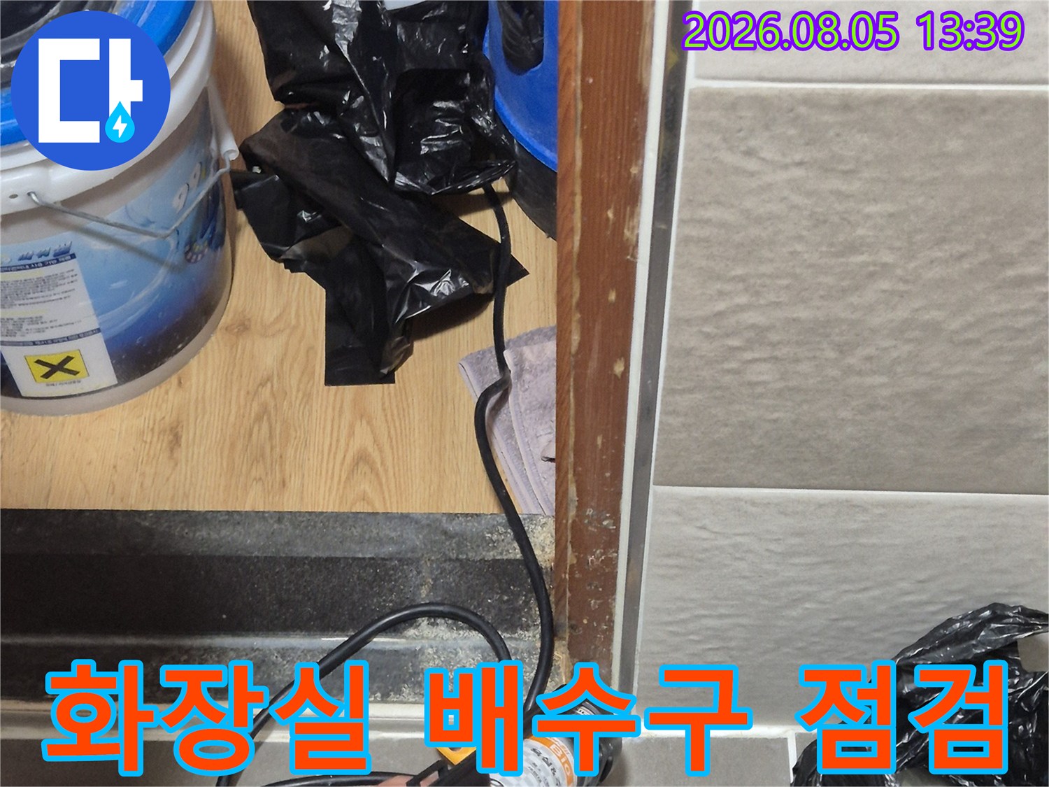 화장실 바닥 배수구 부위의 누수 여부를 확인하기 위해 장비를 사용하여 정밀 점검을 진행하는 모습