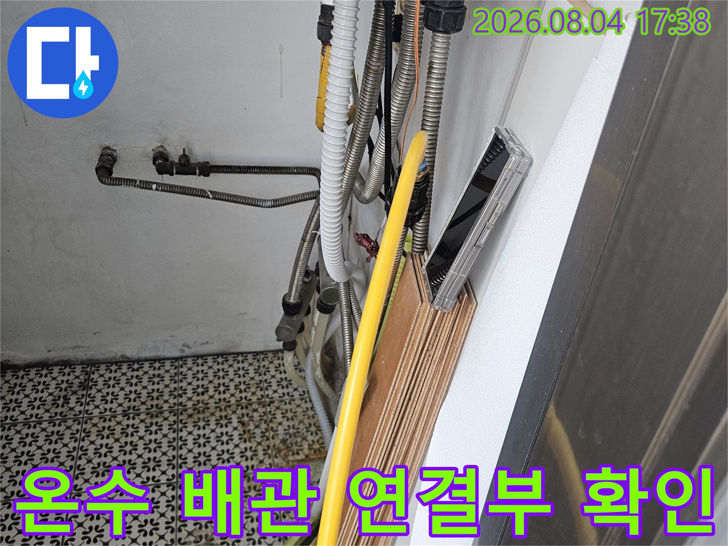주방 싱크대 하단에 위치한 노란색 보온재 덮개와 배관 시스템