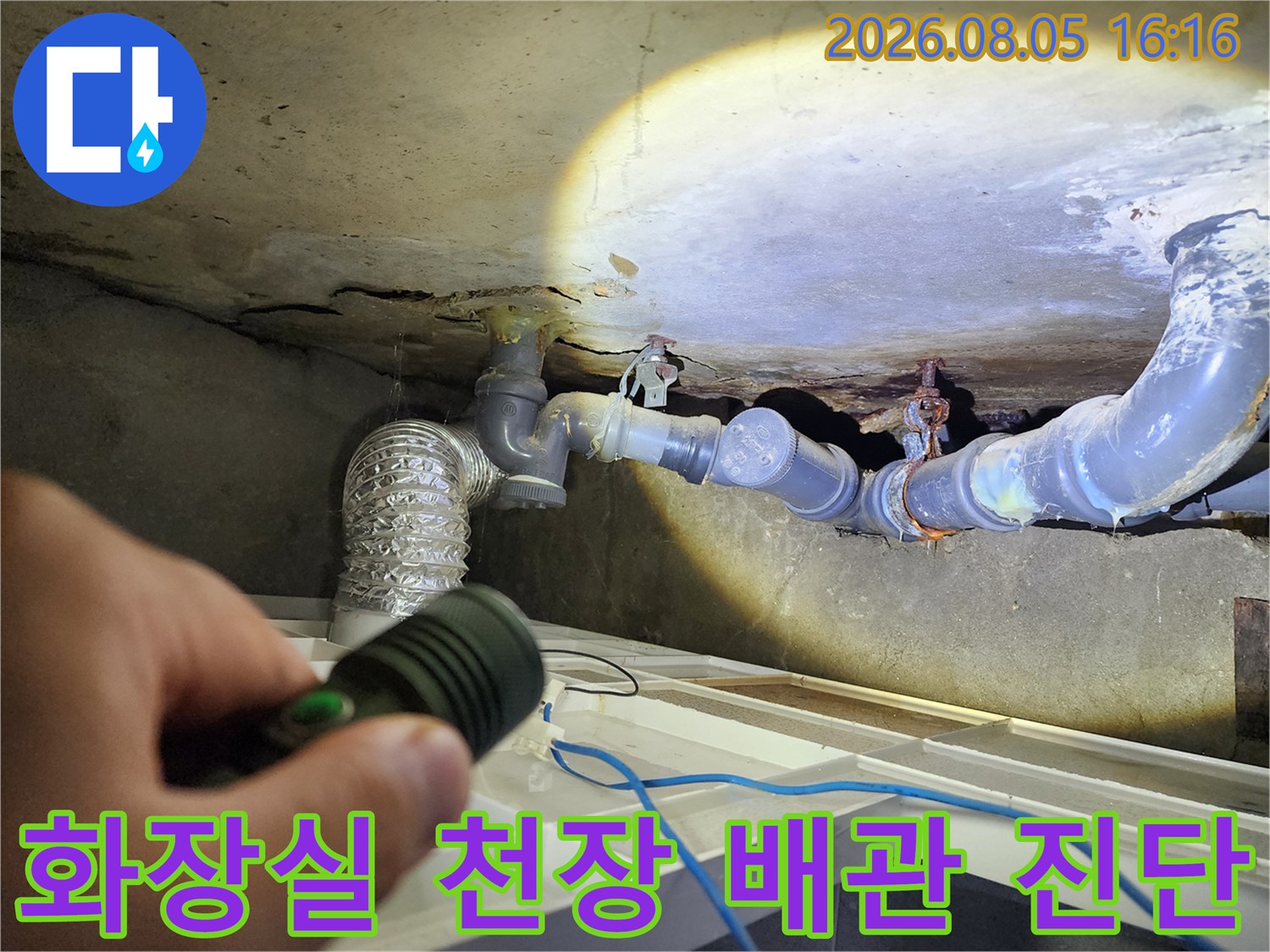 어두운 화장실 천장 공간을 손전등으로 비추며 배관 연결부 점검