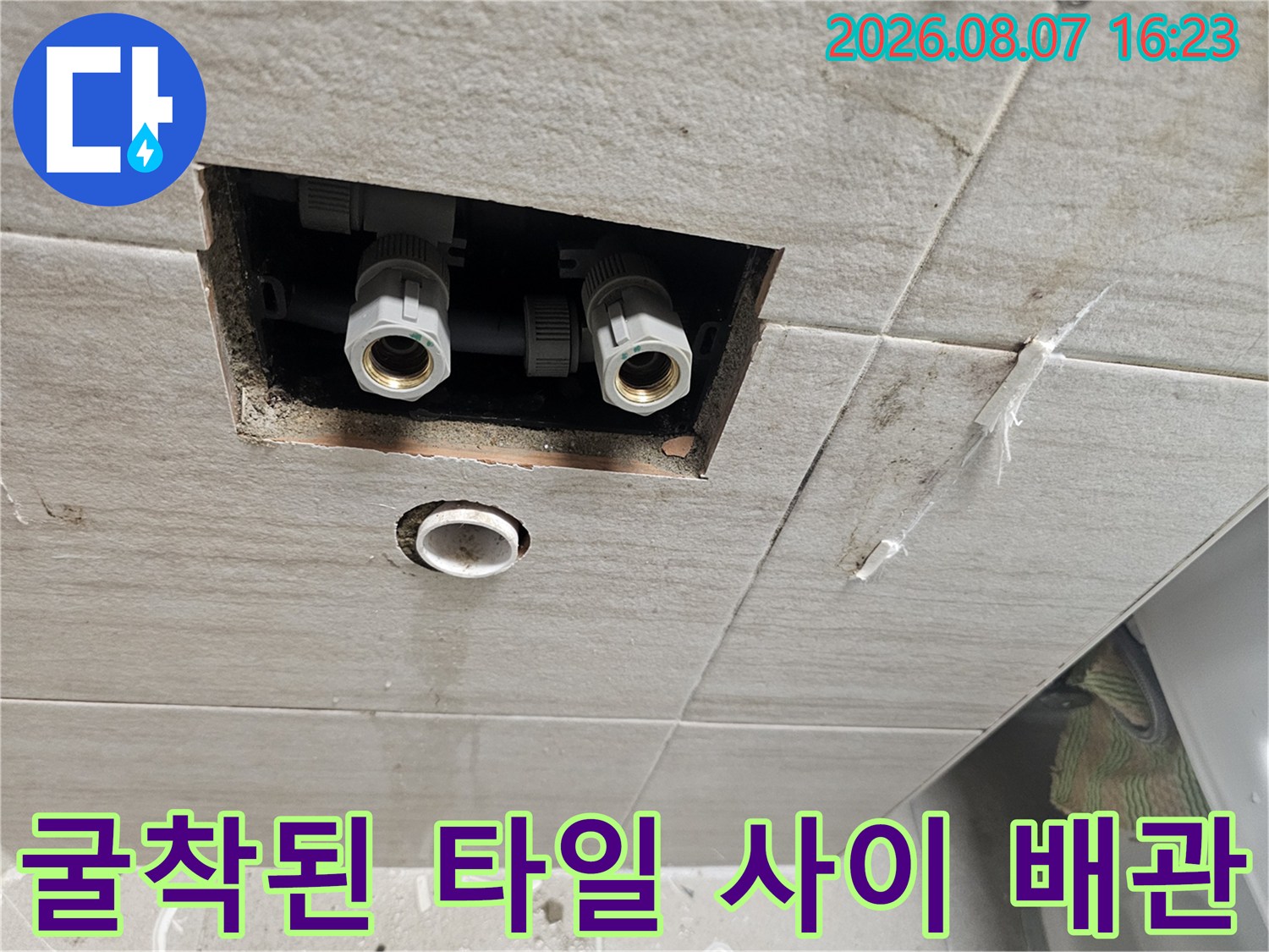 타일을 제거하여 노출시킨 화장실 벽면 급수 배관 및 연결 부속 사진입니다.