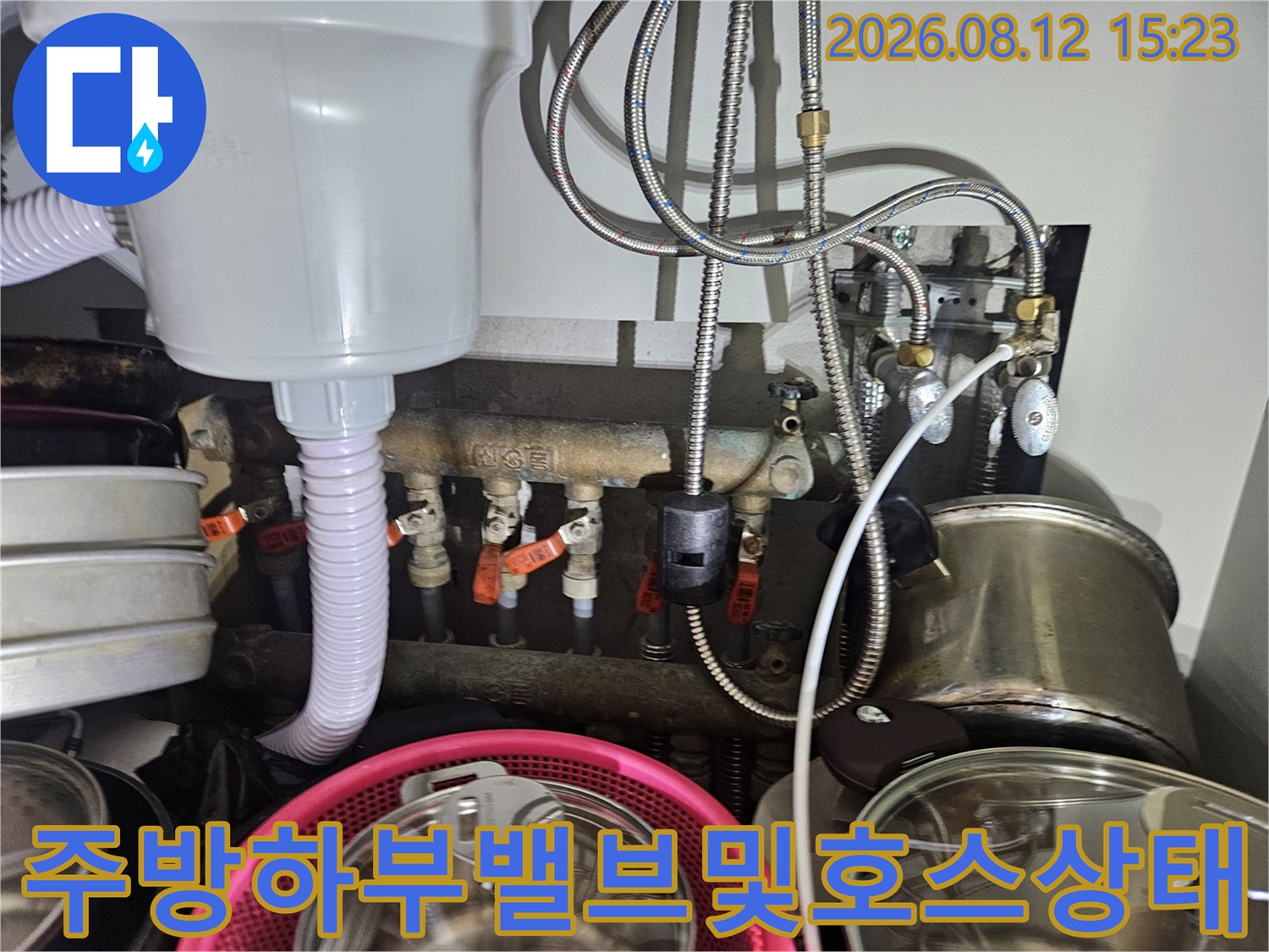 싱크대 아래쪽에 설치된 급수 밸브들과 스테인리스 소재의 배관 호스들