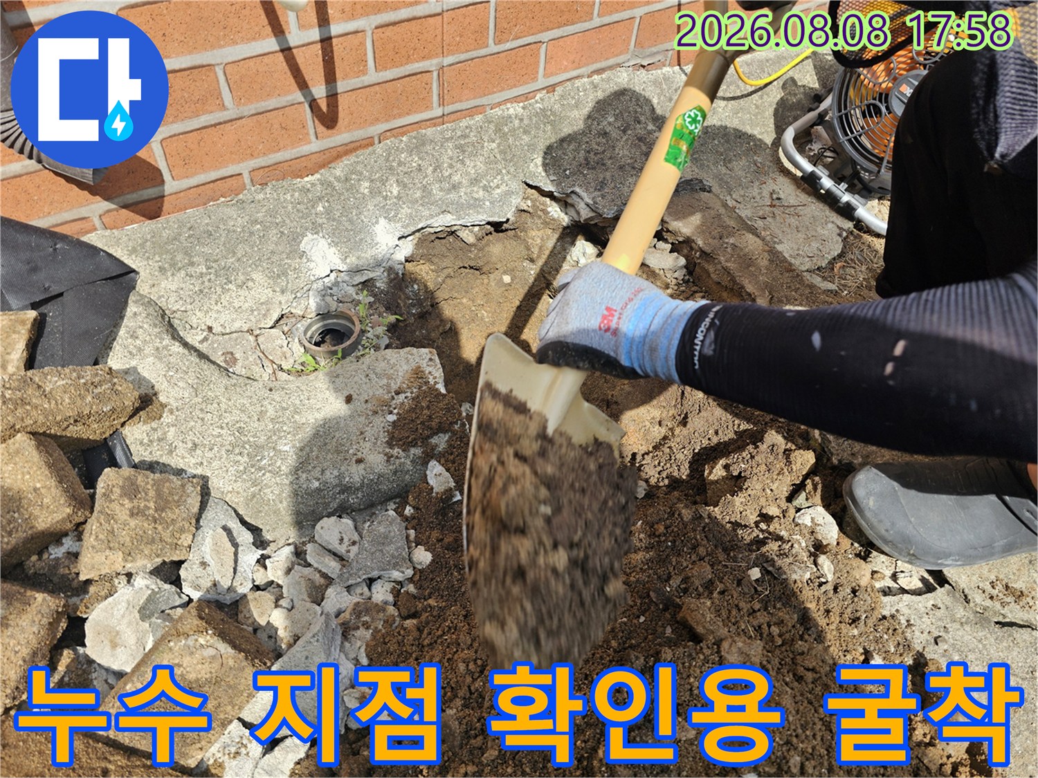 삽을 사용하여 콘크리트와 흙을 파내어 배관 노출을 시도하는 모습입니다.