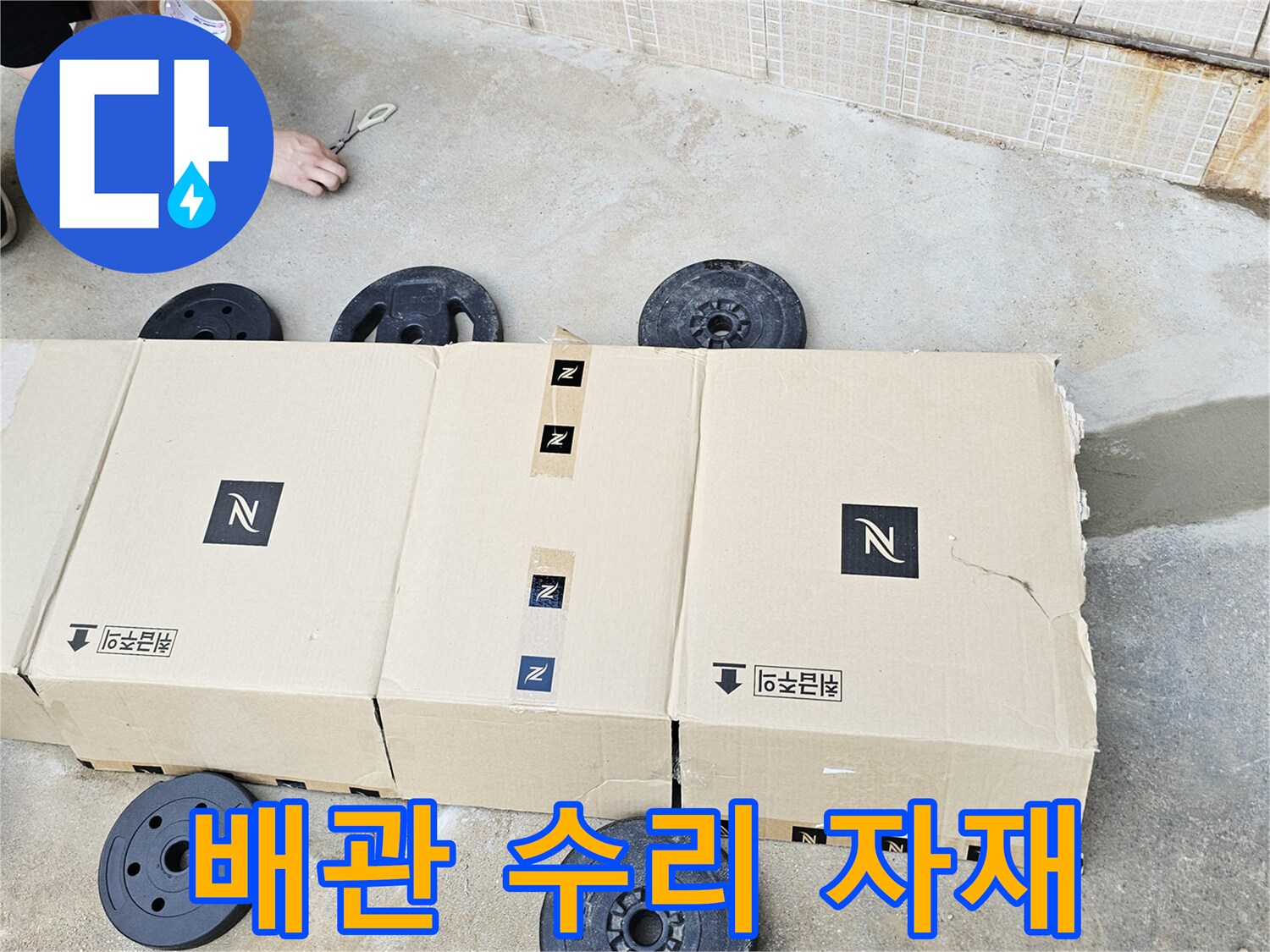 수도 배관 누수 지점을 찾기 위해 현장에 배치된 무거운 무게추와 작업용 박스들입니다.
