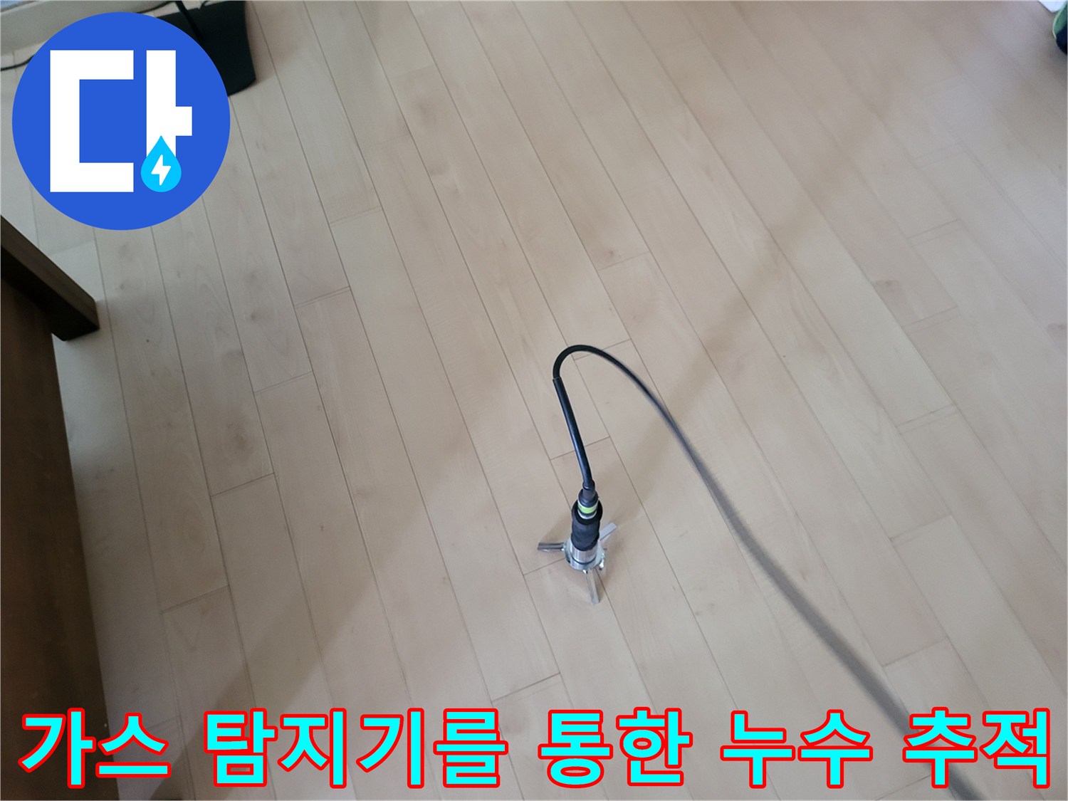 나무 질감의 바닥재 위로 연결된 검사 장비가 배관의 균열 부위를 찾아내고 있습니다.