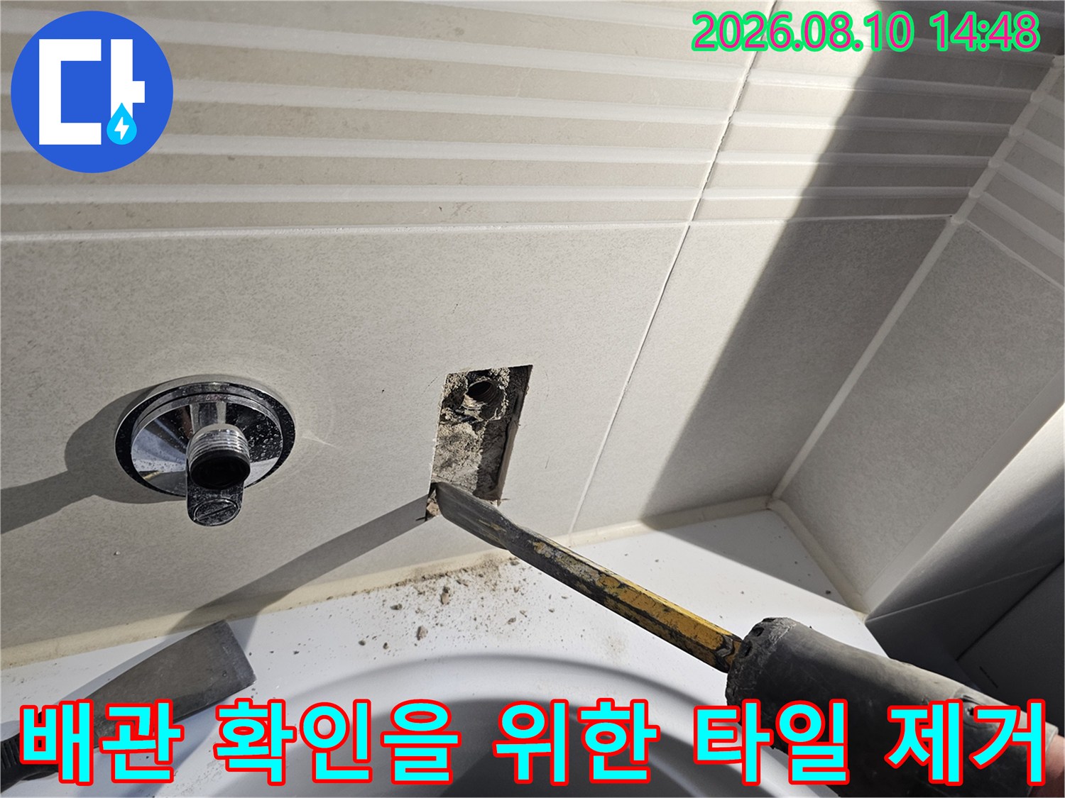 수전 옆 타일 부위를 떼어내고 배관 노출을 위해 정밀하게 작업하는 모습입니다.