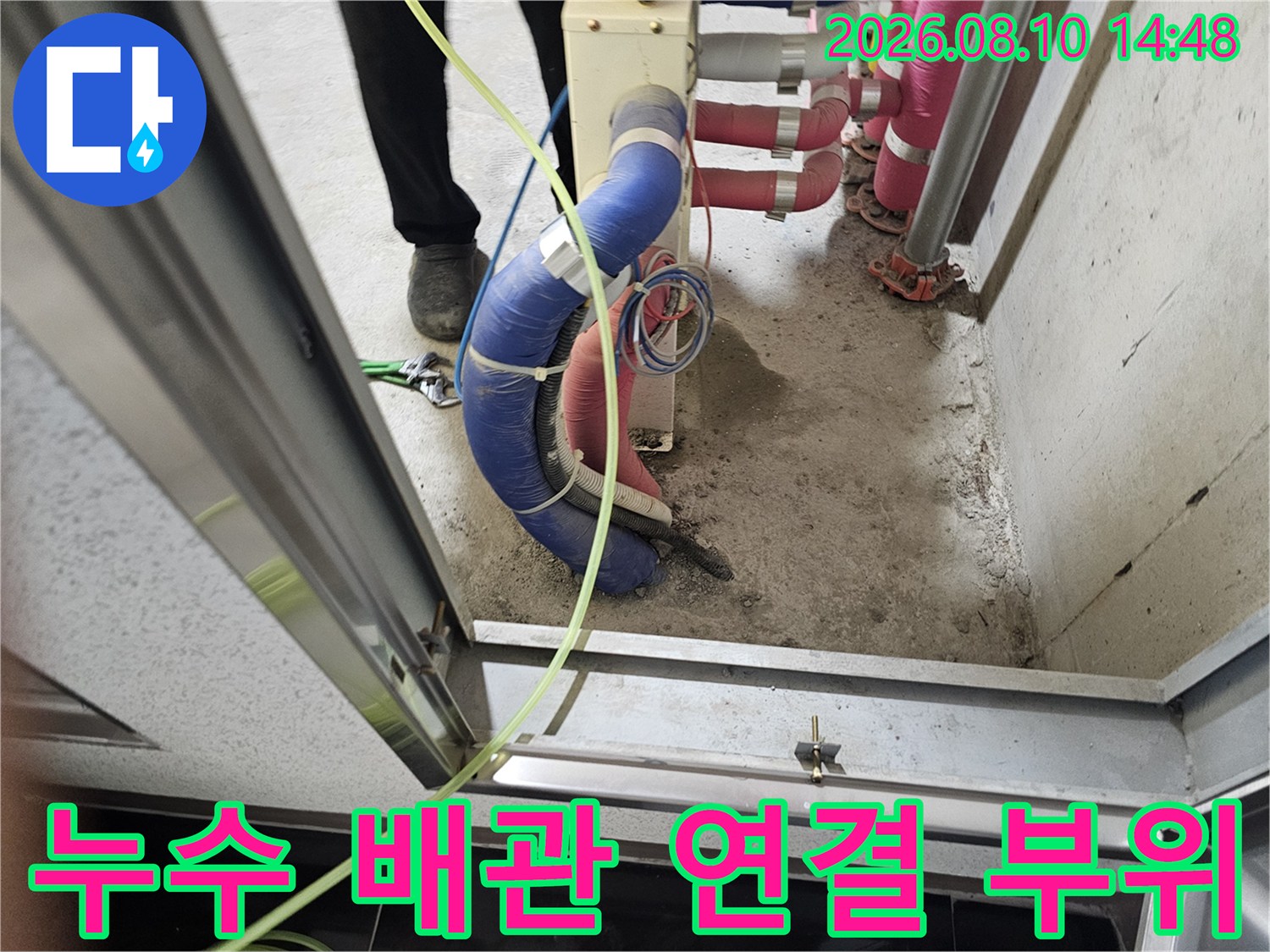 파란색 보온재로 감싸진 배관과 분홍색 배근이 교차하는 천장 내부 모습입니다.