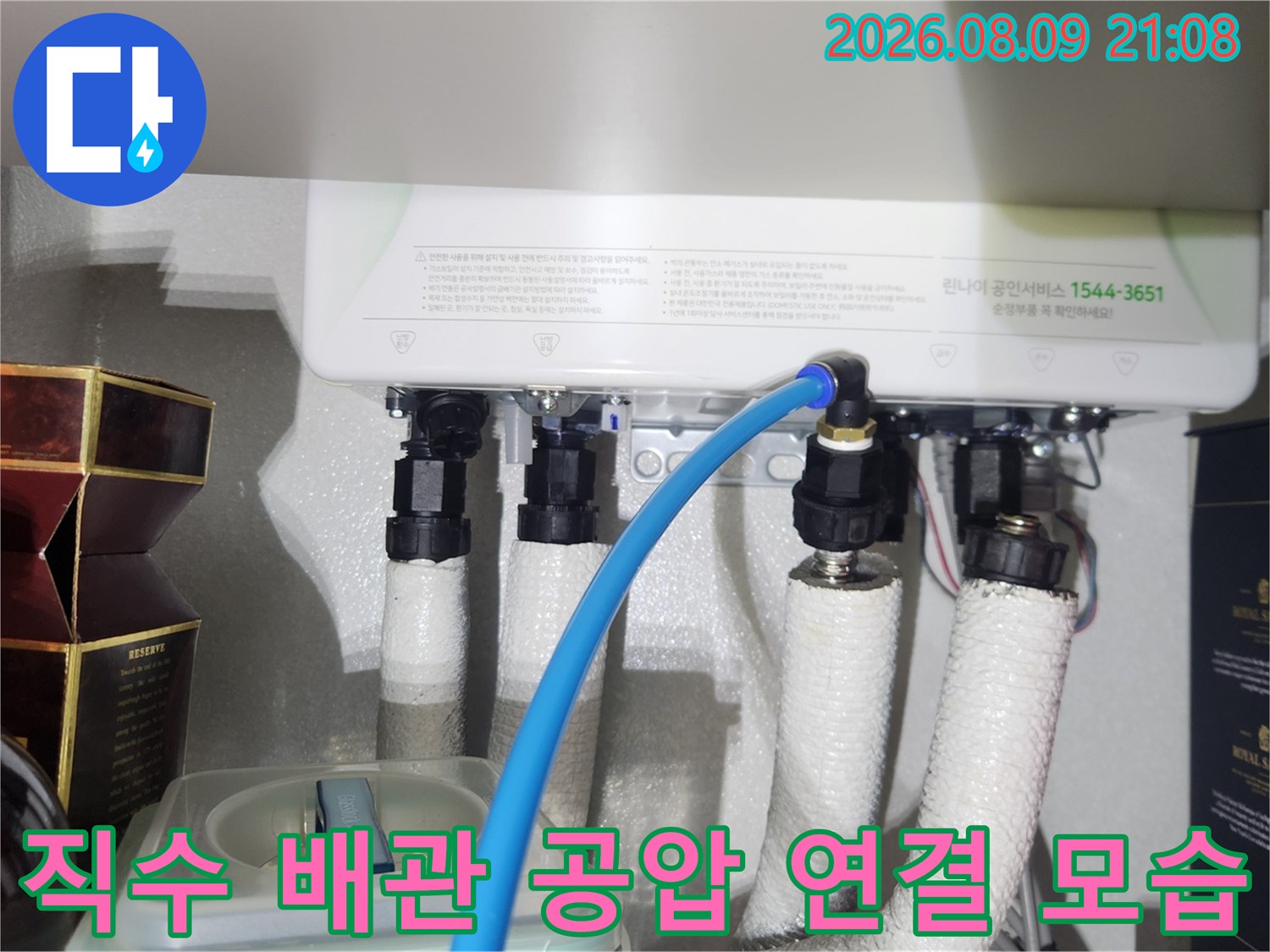 보일러실 하단 배관에 파란색 호스를 연결하여 공압 검사를 진행하는 장면