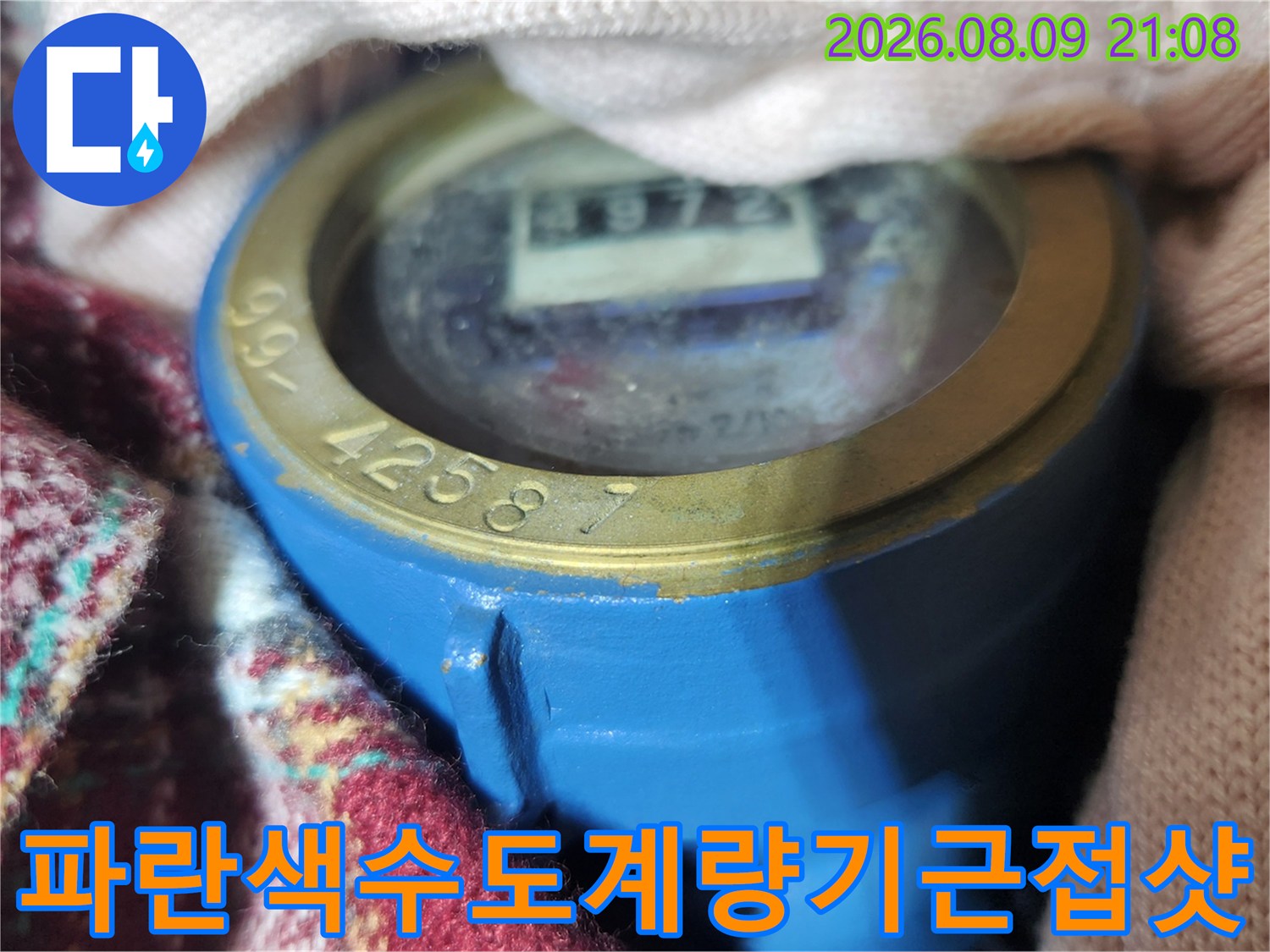 숫자가 표시된 창과 별침이 있는 파란색 수도 계량기의 상단부 사진