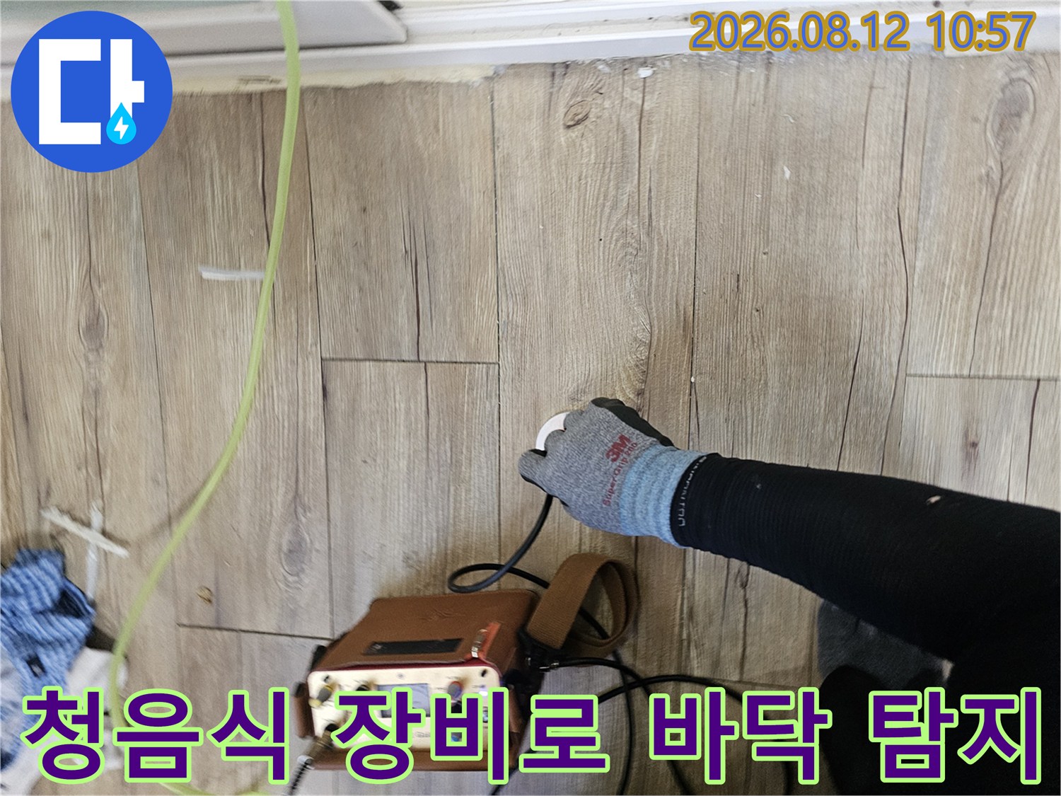 나무 바닥재 위에서-청음식 탐지기를 사용하여-배관 누수 지점을 찾는 모습