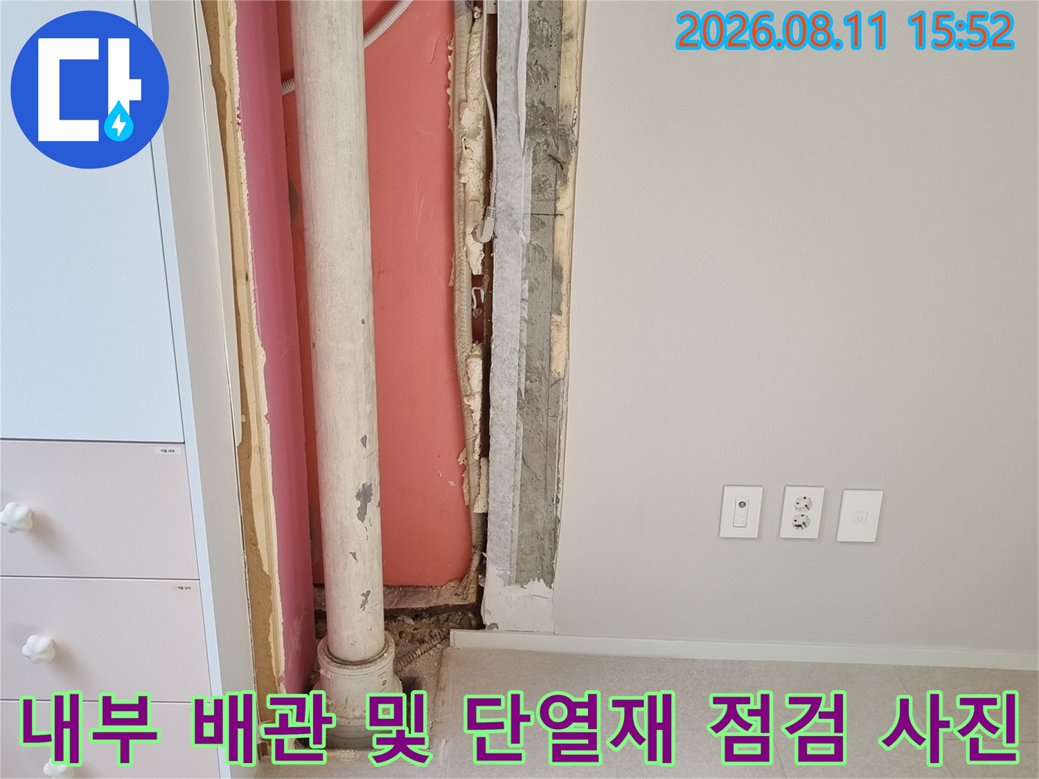 벽면의 일부를 제거하여 내부의 우수관과 분홍색 단열재-그리고 드레인 호스를 노출시킨 장면