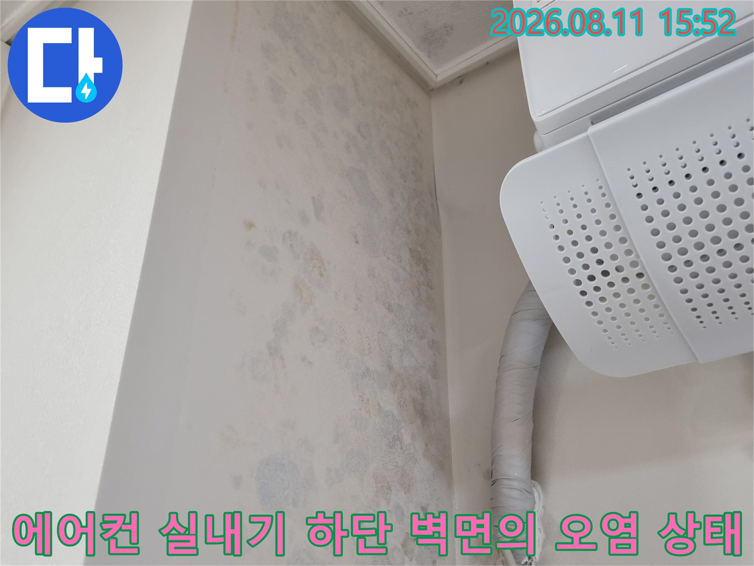 천장에 부착된 에어컨과 그 옆의 보온재 배관 그리고 벽면에 핀 회색빛 곰팡이 자국들