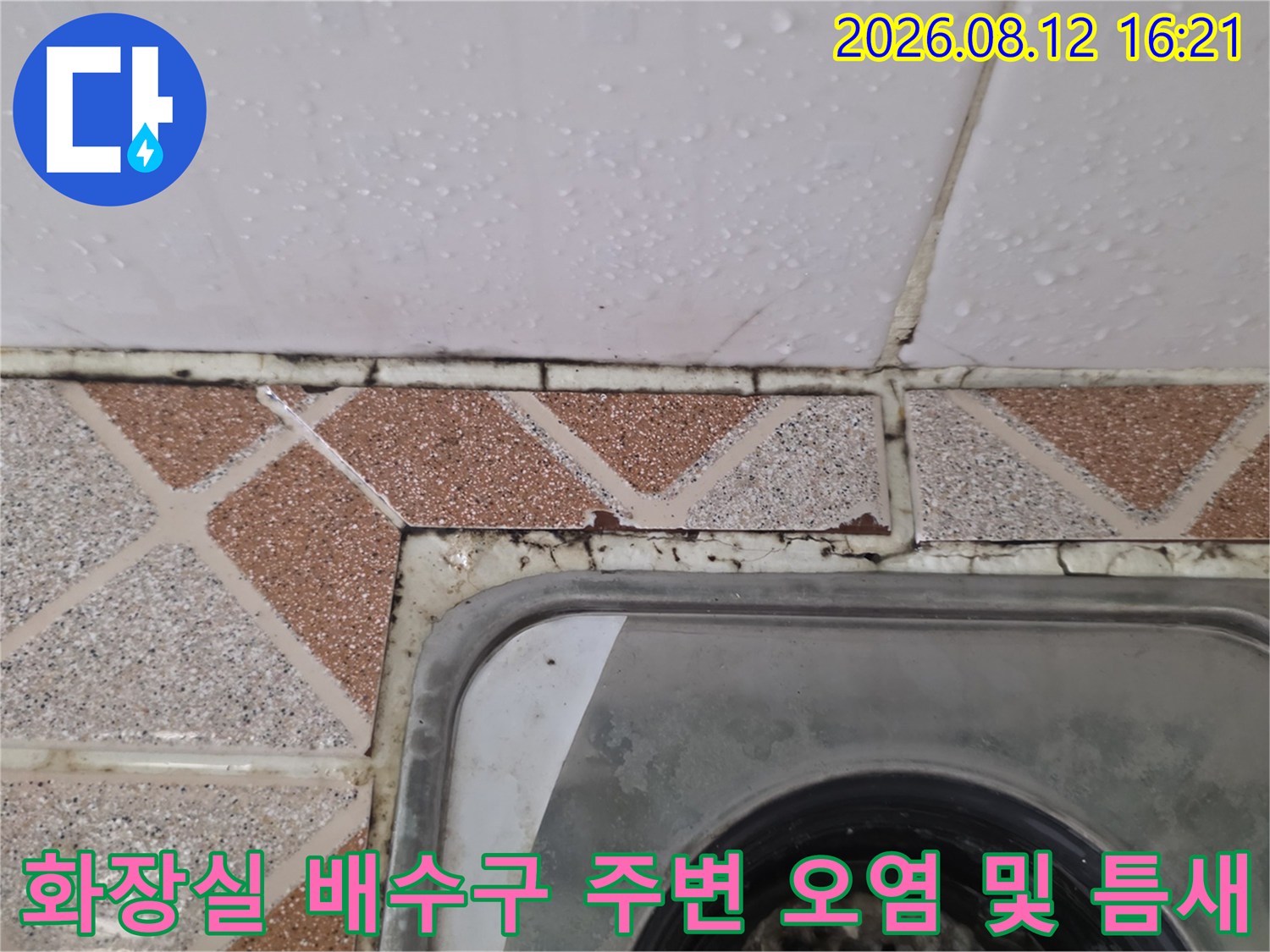 갈색-패턴-타일과-금속-배수구가-만나는-지점의-노후된-줄눈-상태