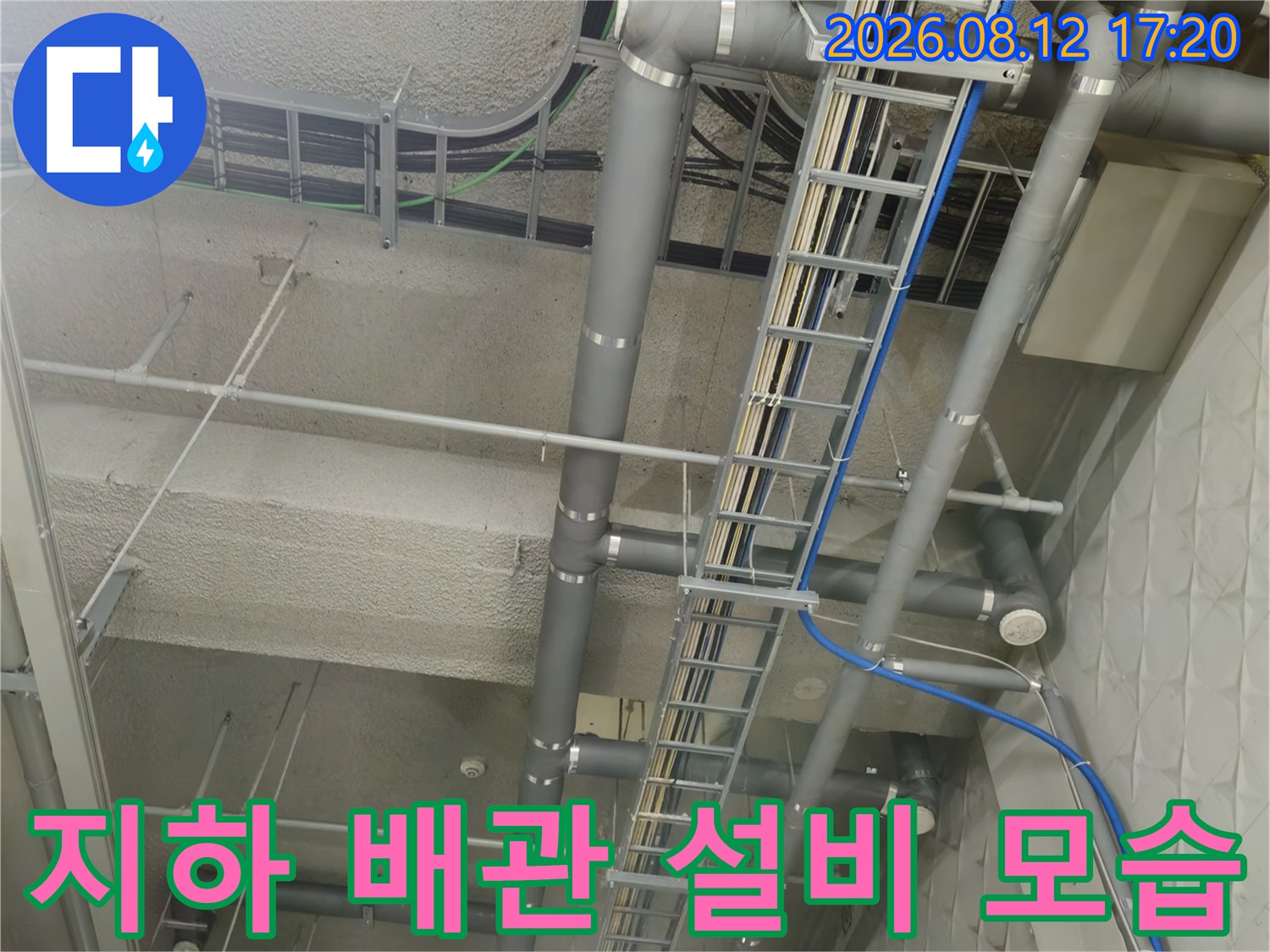 상가 지하 주차장 천장에 설치된 복잡한 배수 및 전기 배선 구조