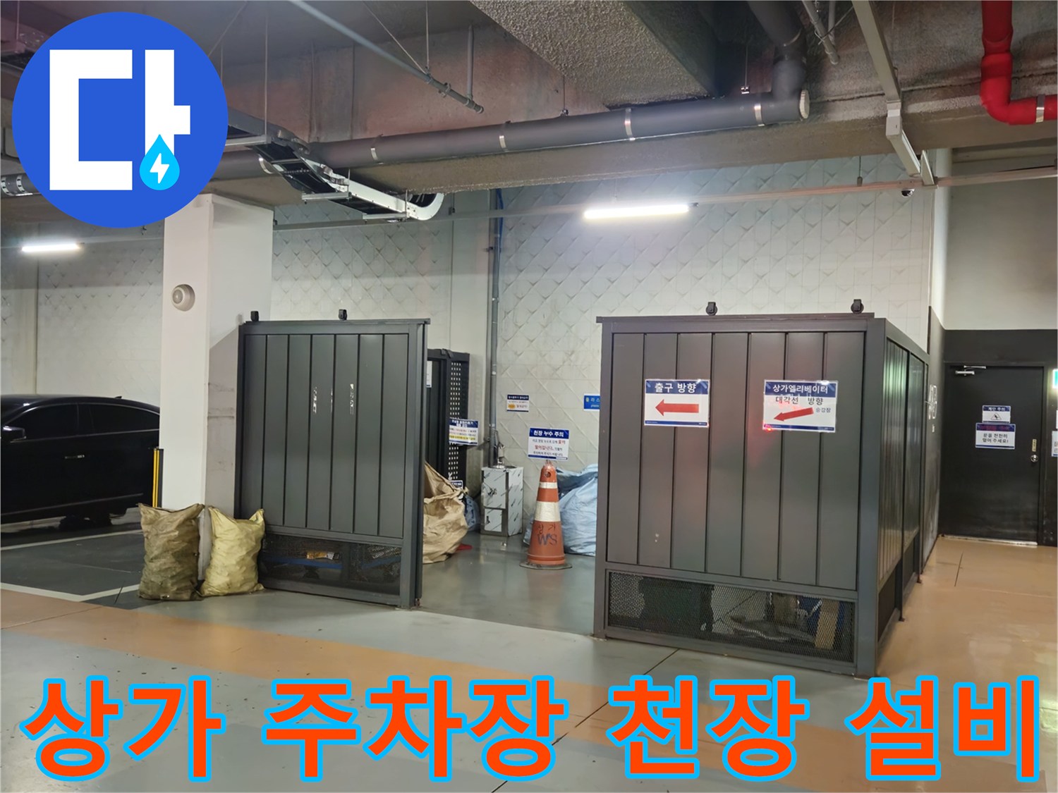 지하 주차장 내 설치된 은색 배관과 전기 배선 구조물