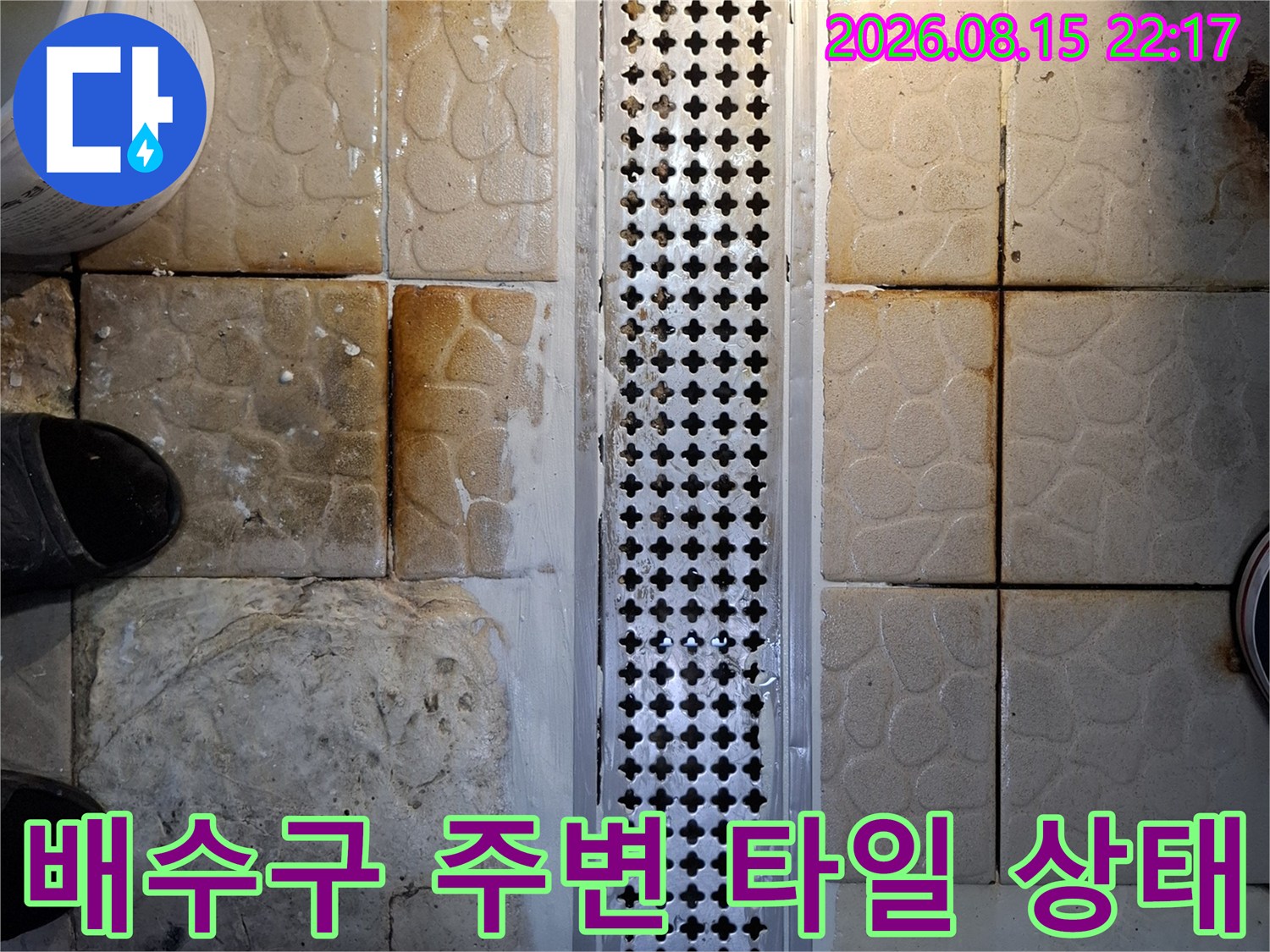 스테인리스 배수 트렌치와 오염된 타일의 근접 촬영 이미지입니다.