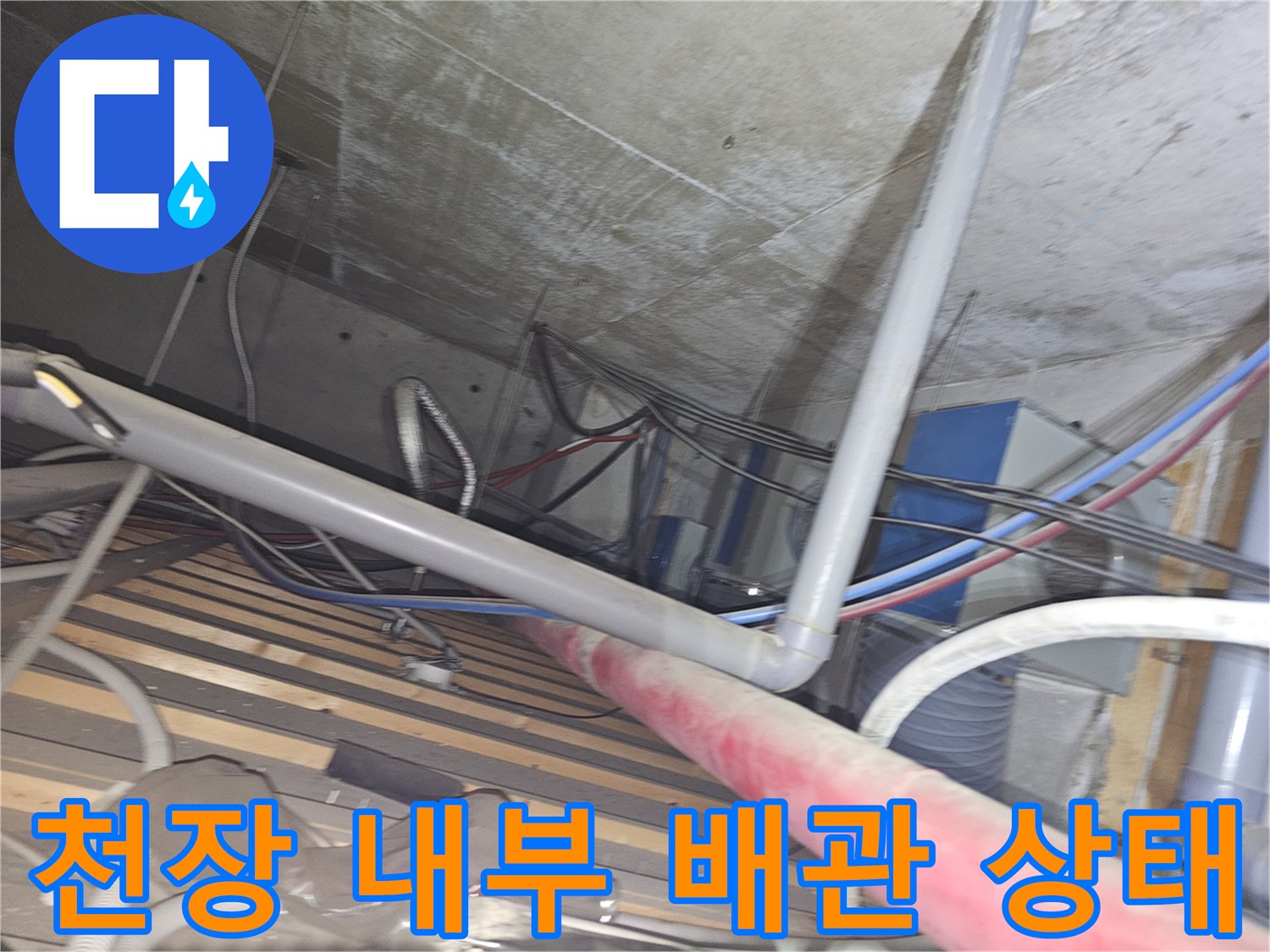 상가 천장 구조물-복잡하게 얽힌 배관과 습윤된 콘크리트 표면